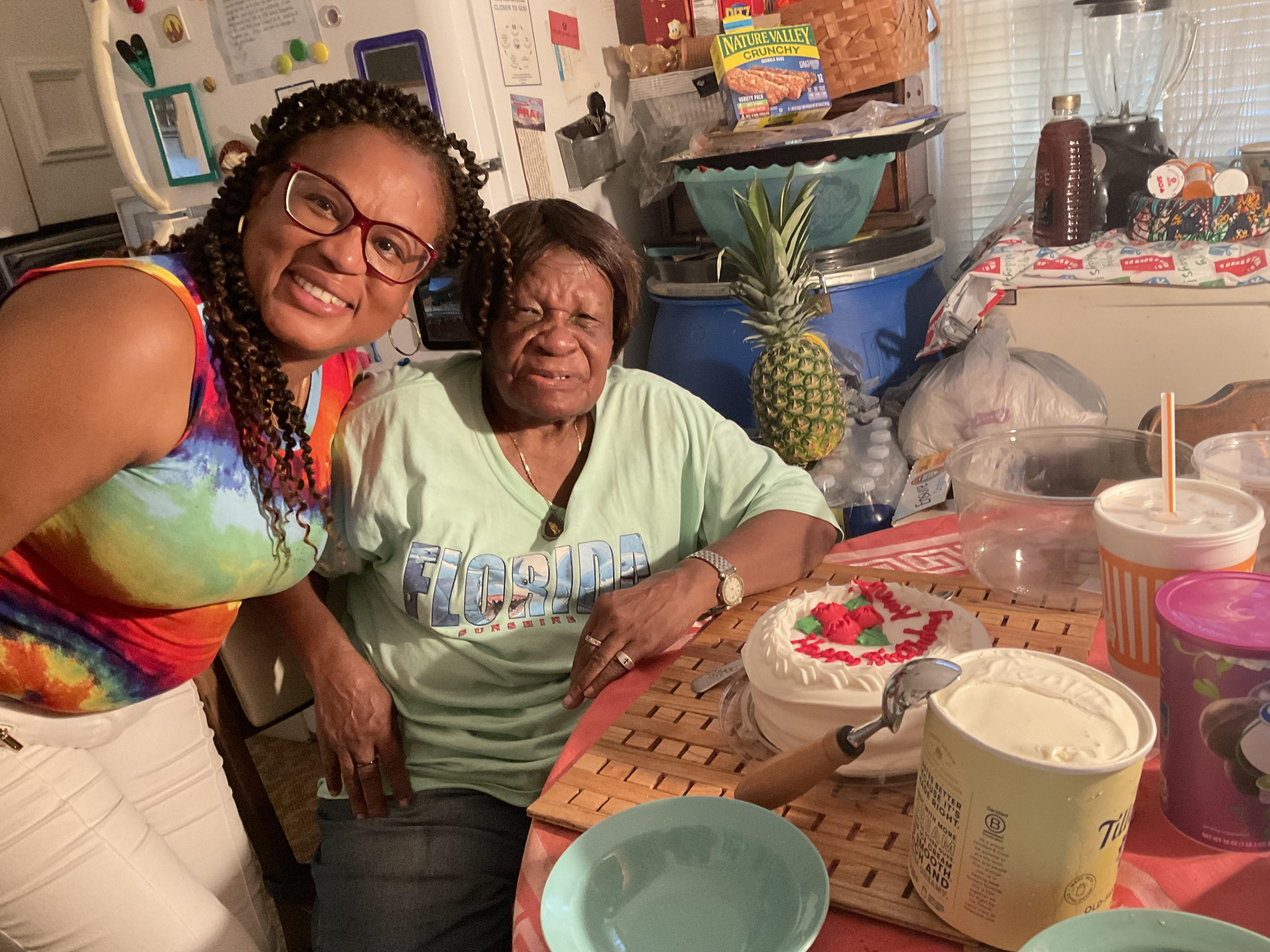 Two women standing next to a table with food