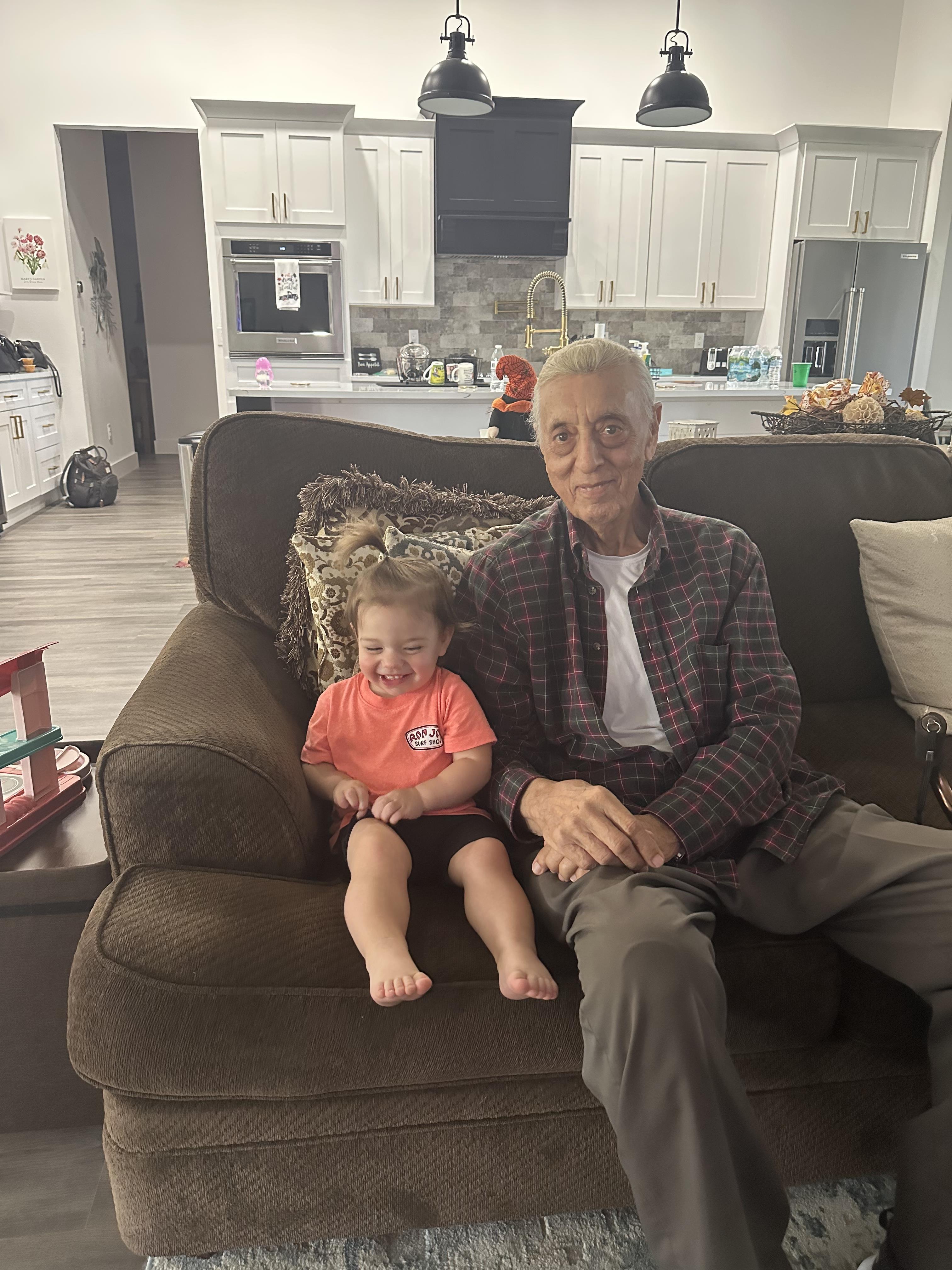 An old man and a baby sitting on a couch
