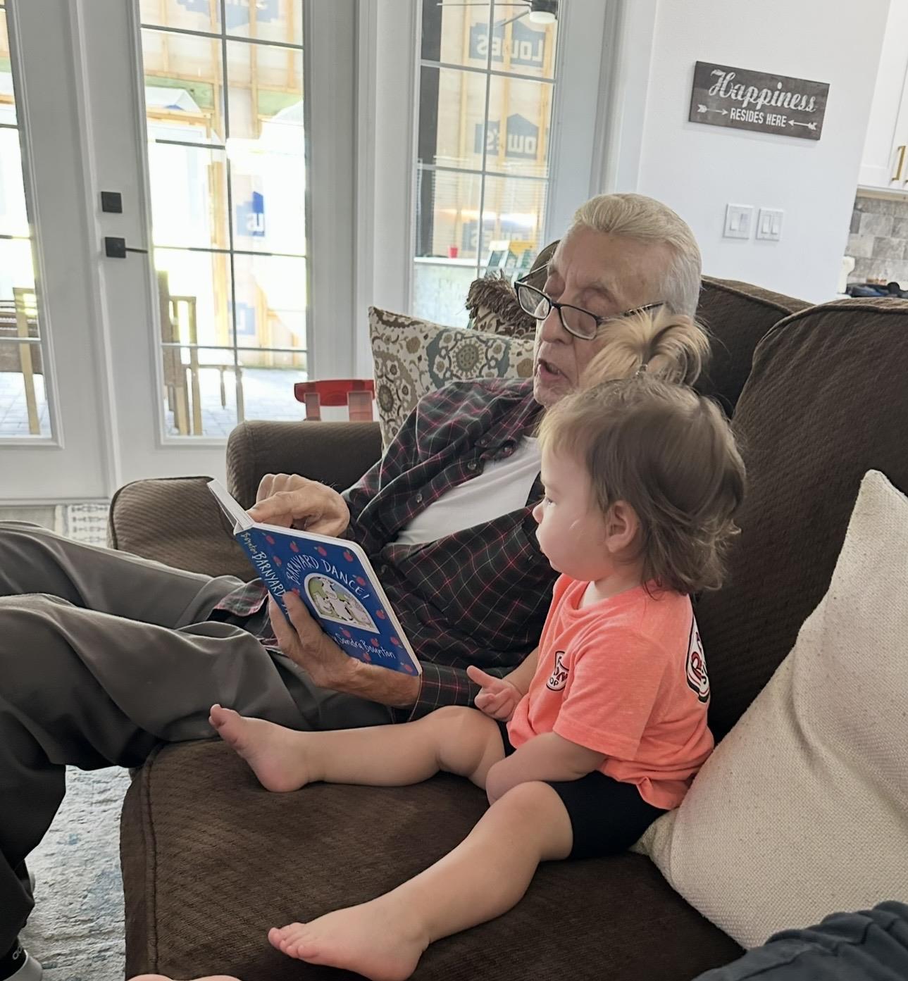 A man and child sitting on a couch reading a book