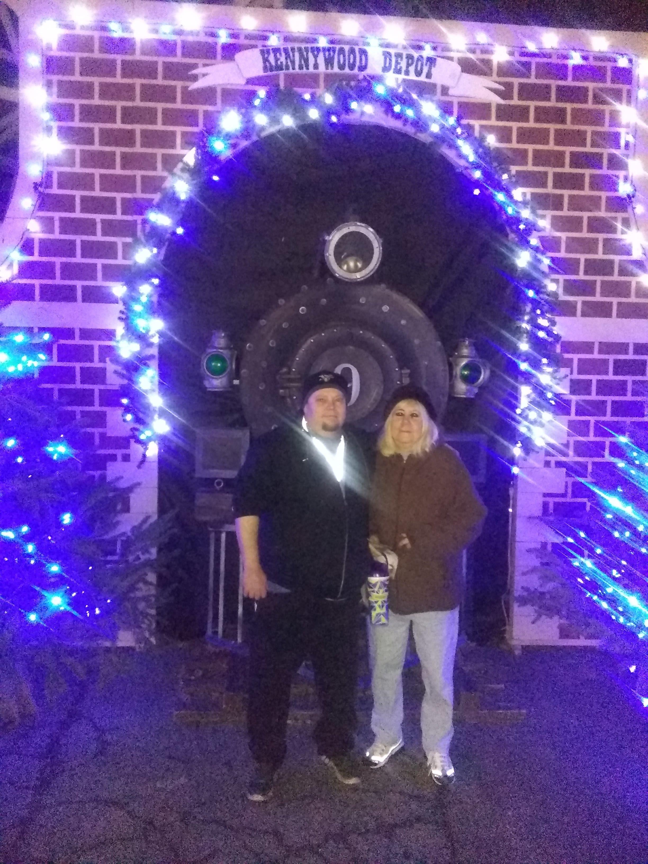 A man and woman standing in front of a brick building with blue lights