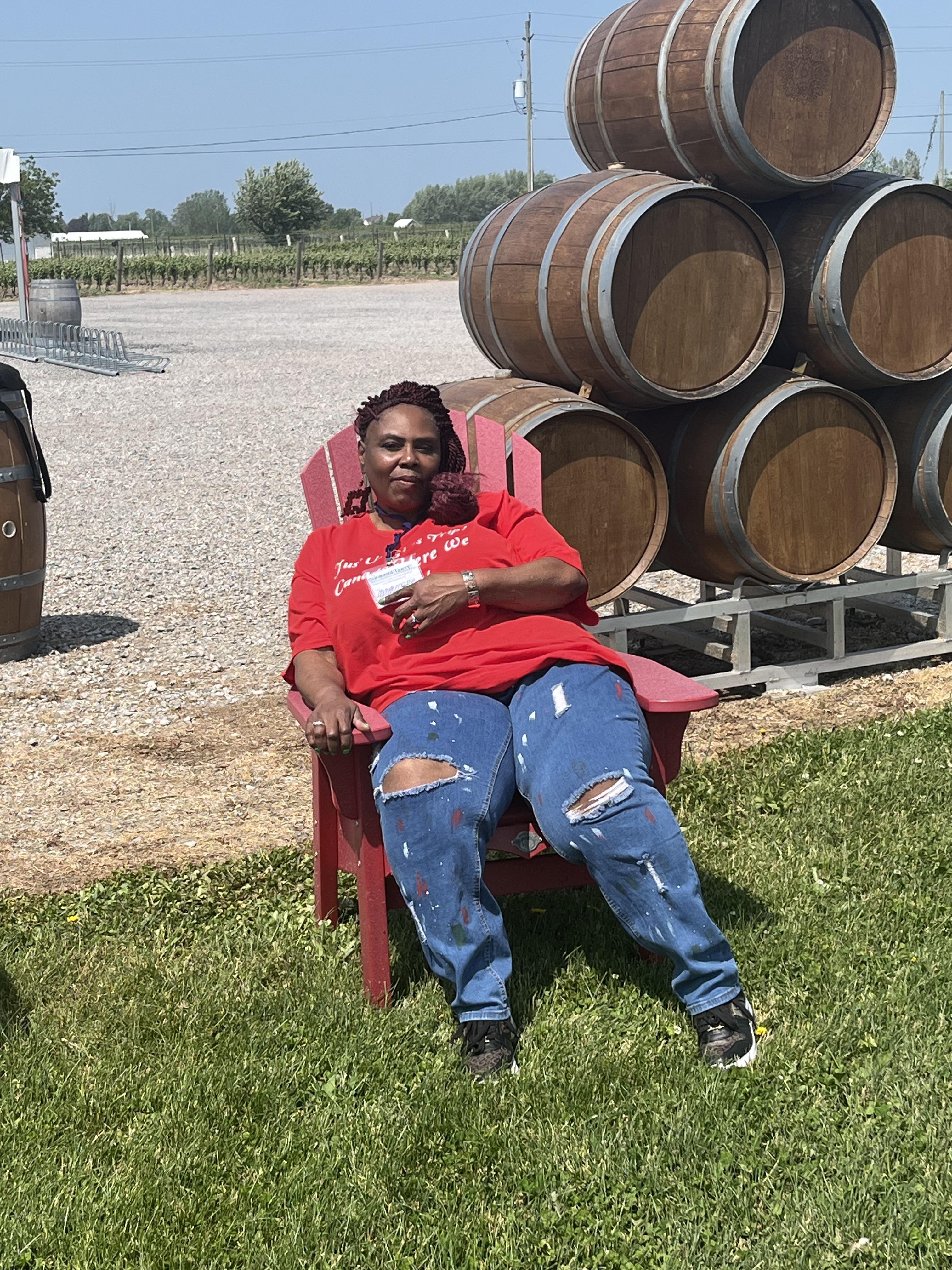 A woman sitting in a red chair with a stack of barrels