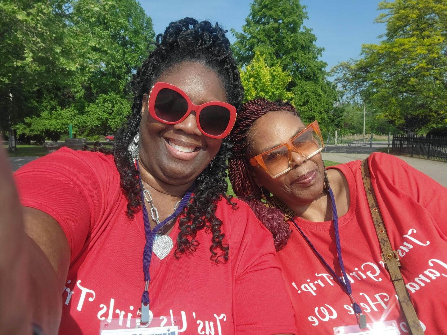 Two women wearing red shirts and sunglasses