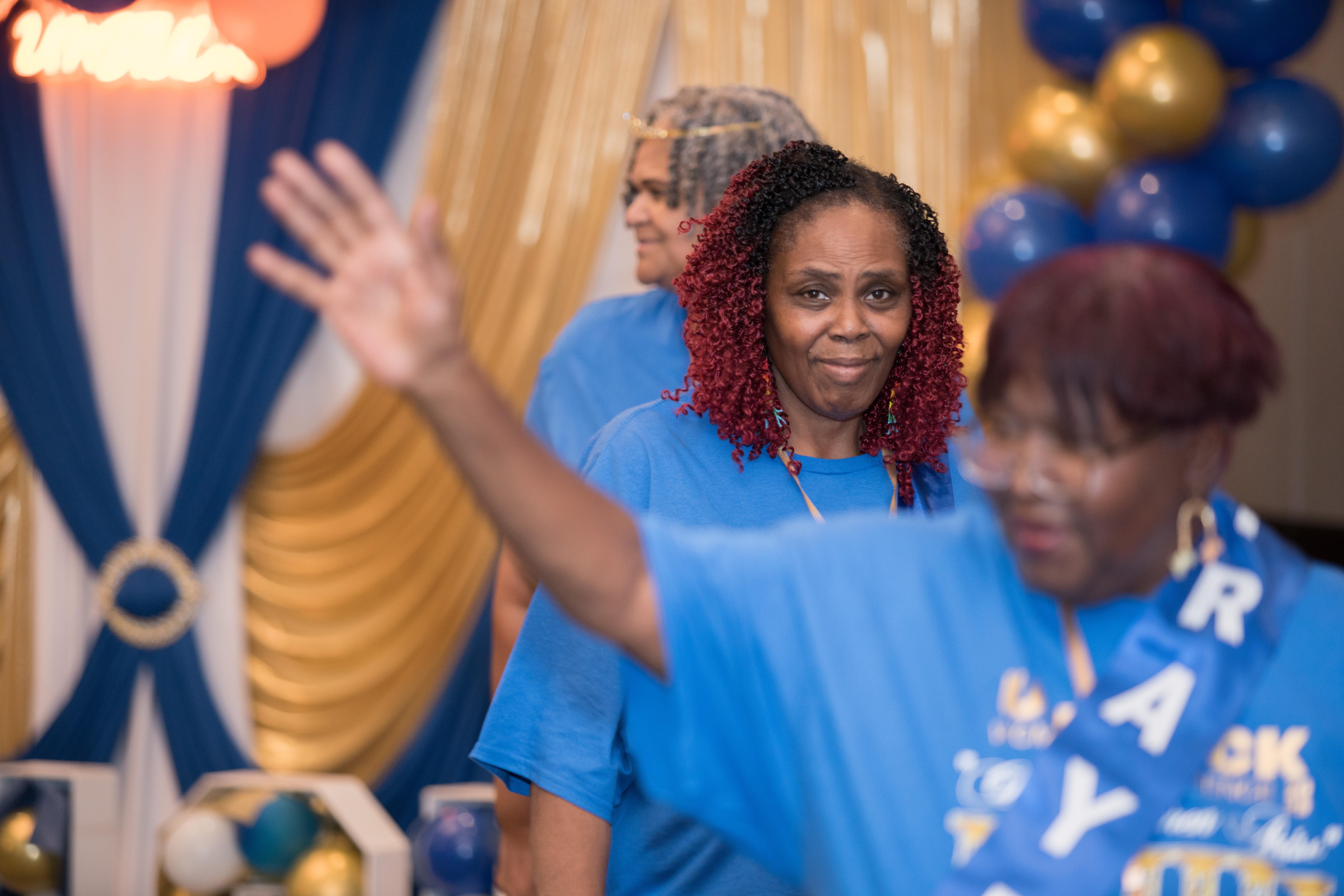 A group of people in blue shirts waving