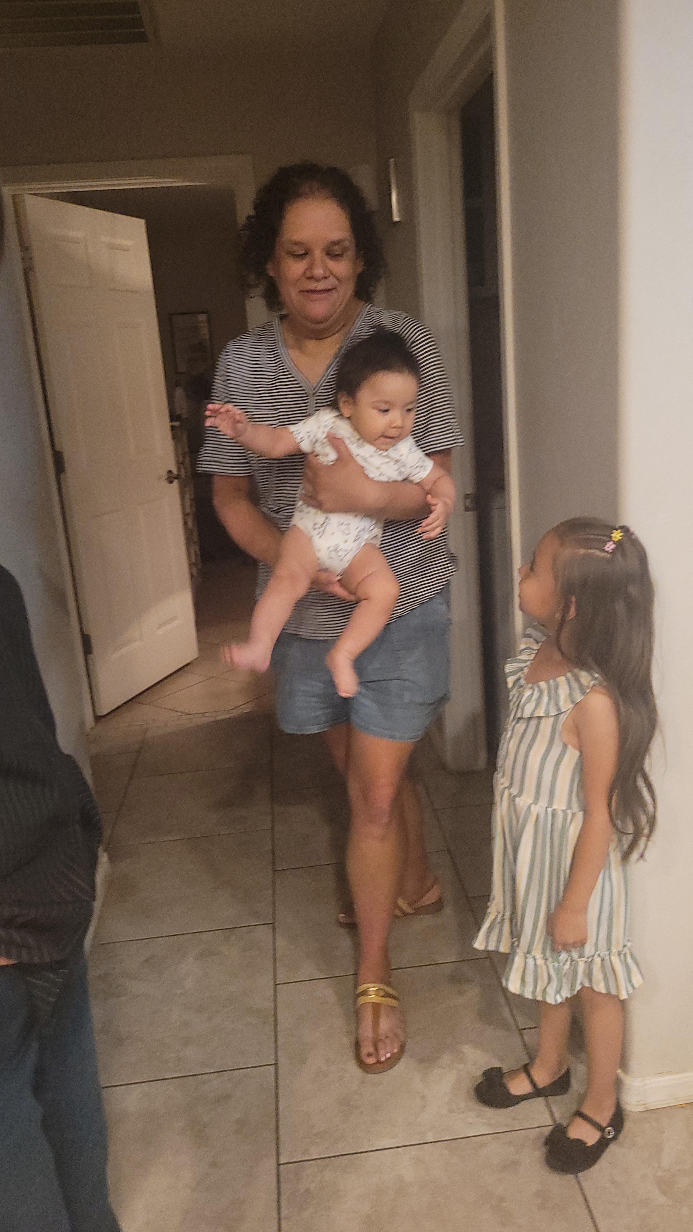 A woman holding a baby and a girl