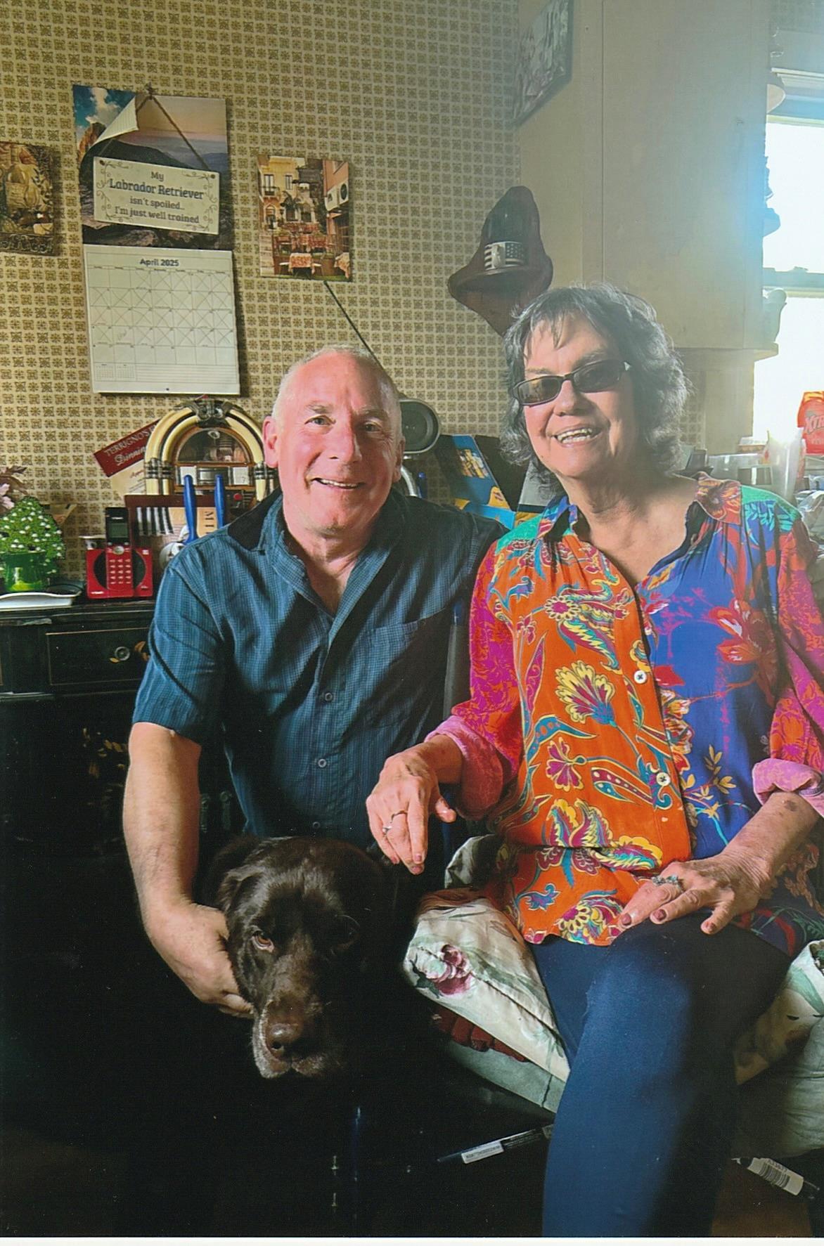 A man and woman sitting in a chair with a dog