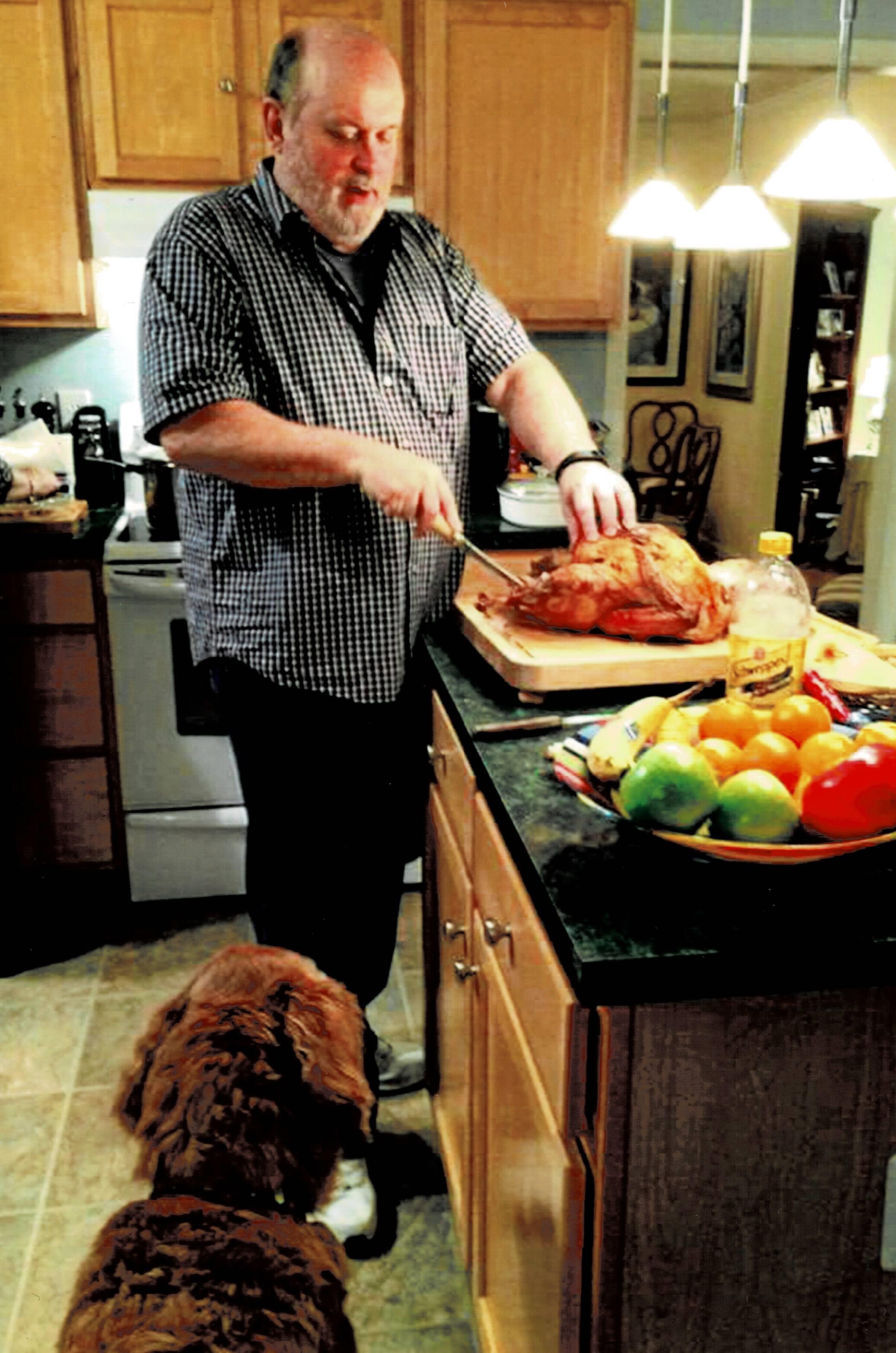 A man cutting a turkey in a kitchen