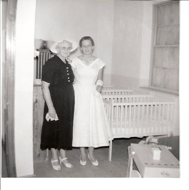 A woman and a woman standing in a room with a crib