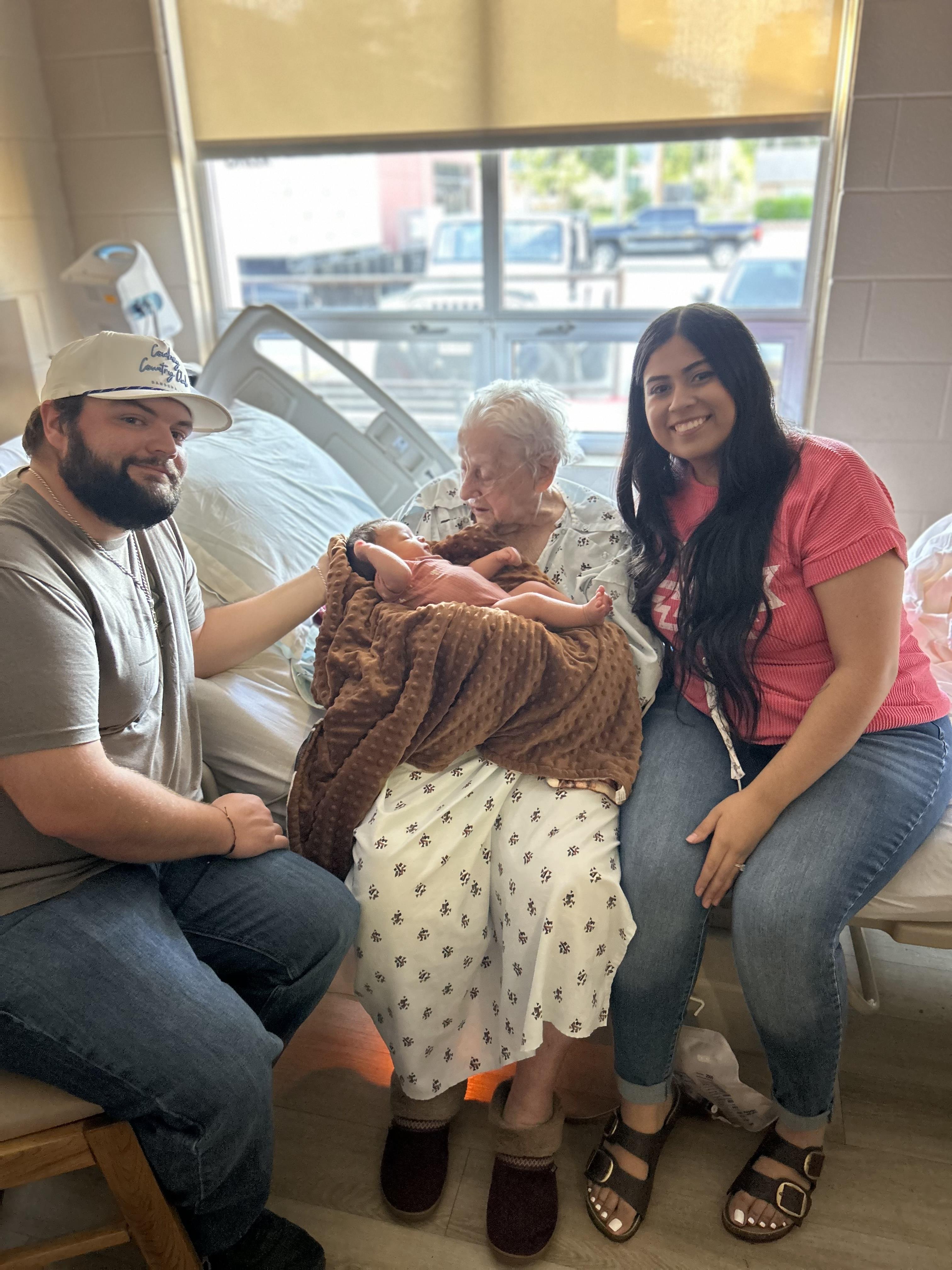 A group of people sitting on a hospital bed with a baby