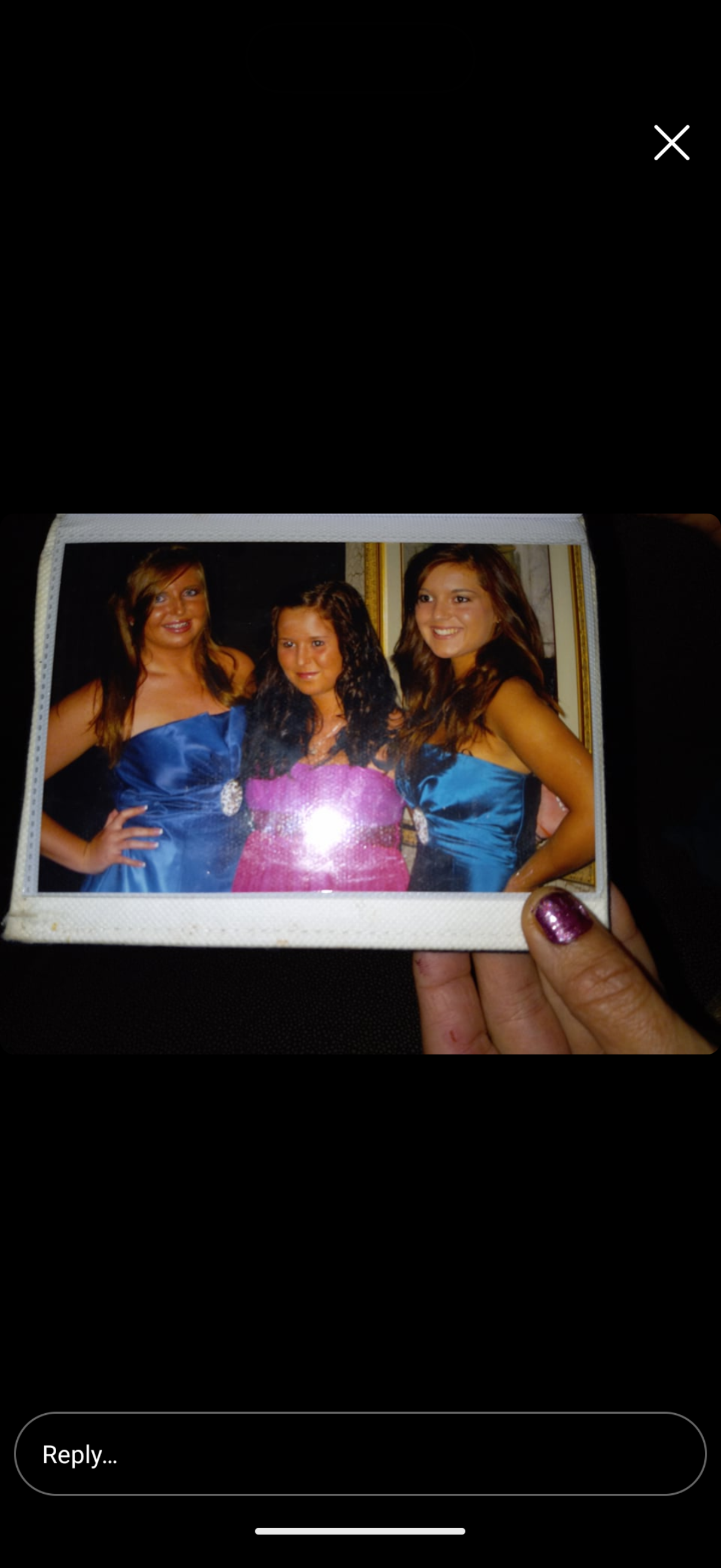 A hand holding a photo of three girls