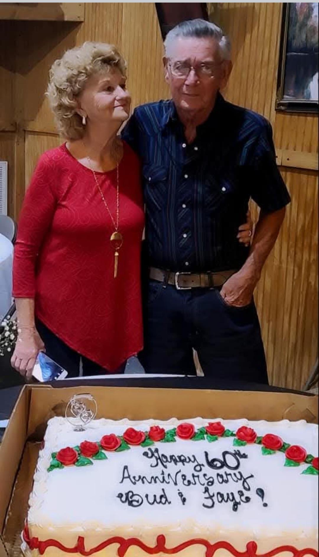 A man and woman standing next to a cake