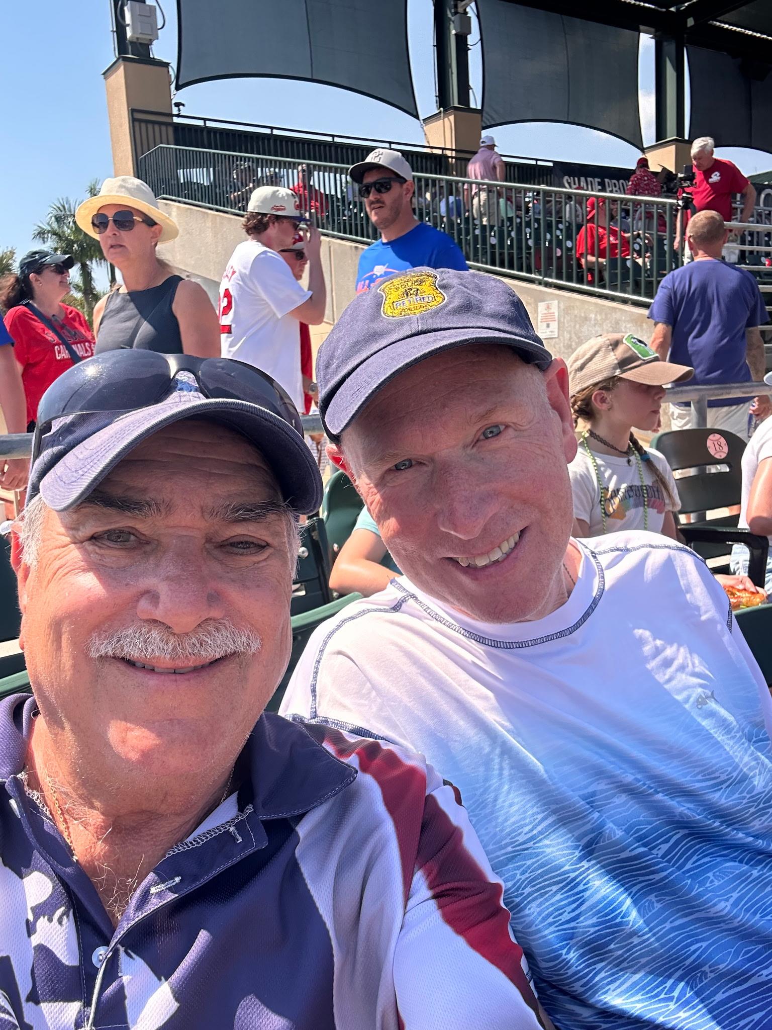 Two men sitting in bleachers and smiling