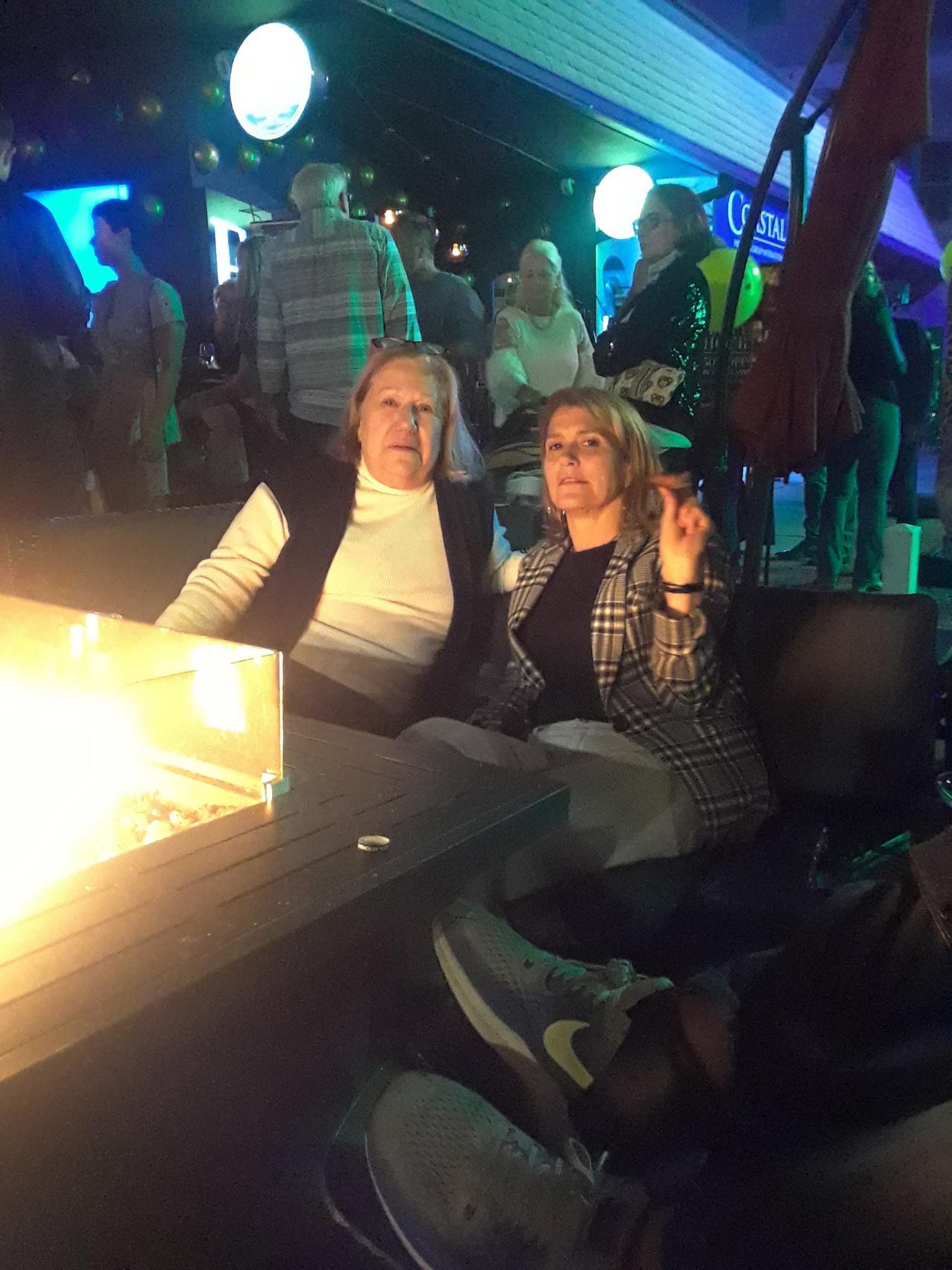 Two women sitting at a table with a fire