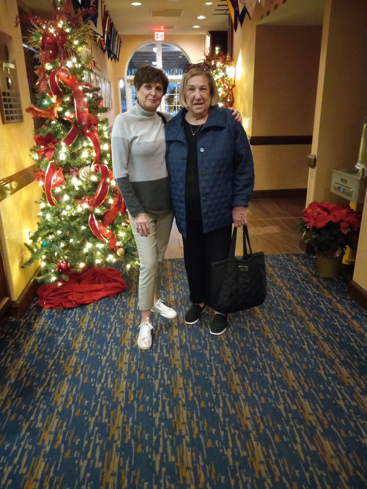 Two women standing in a hallway with a christmas tree