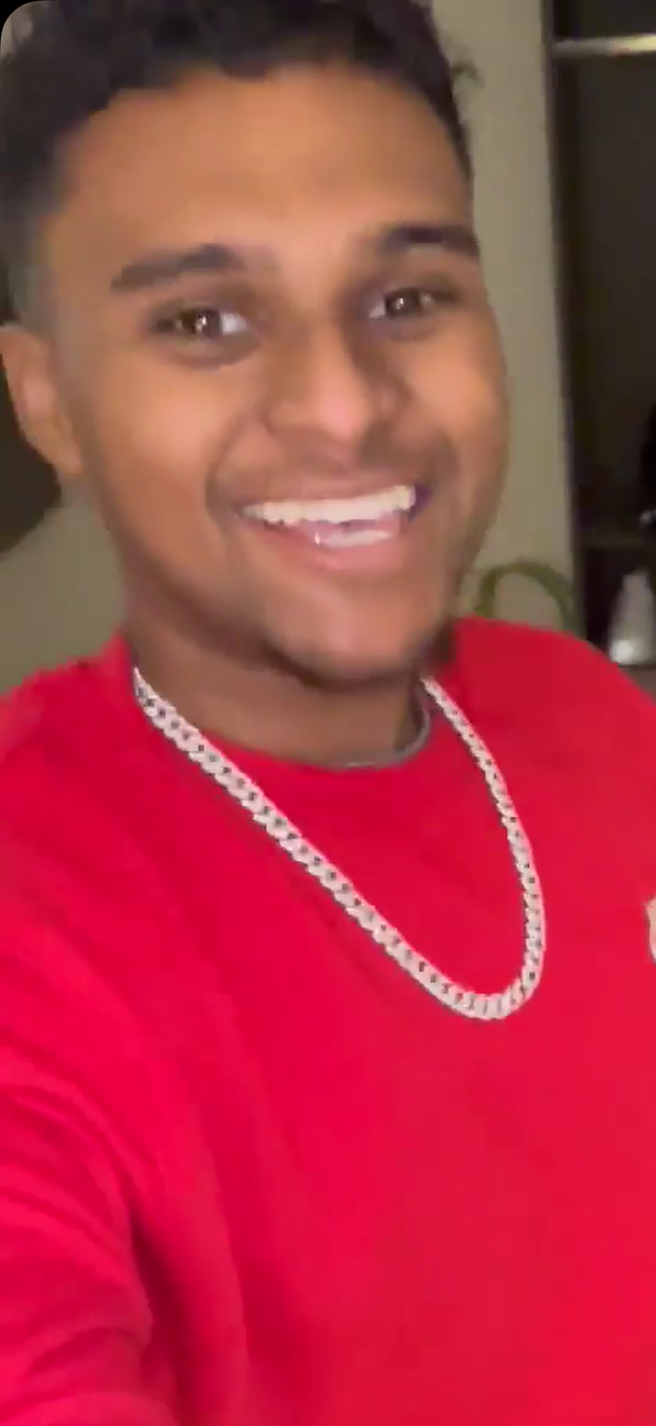 A man wearing a red shirt and a necklace