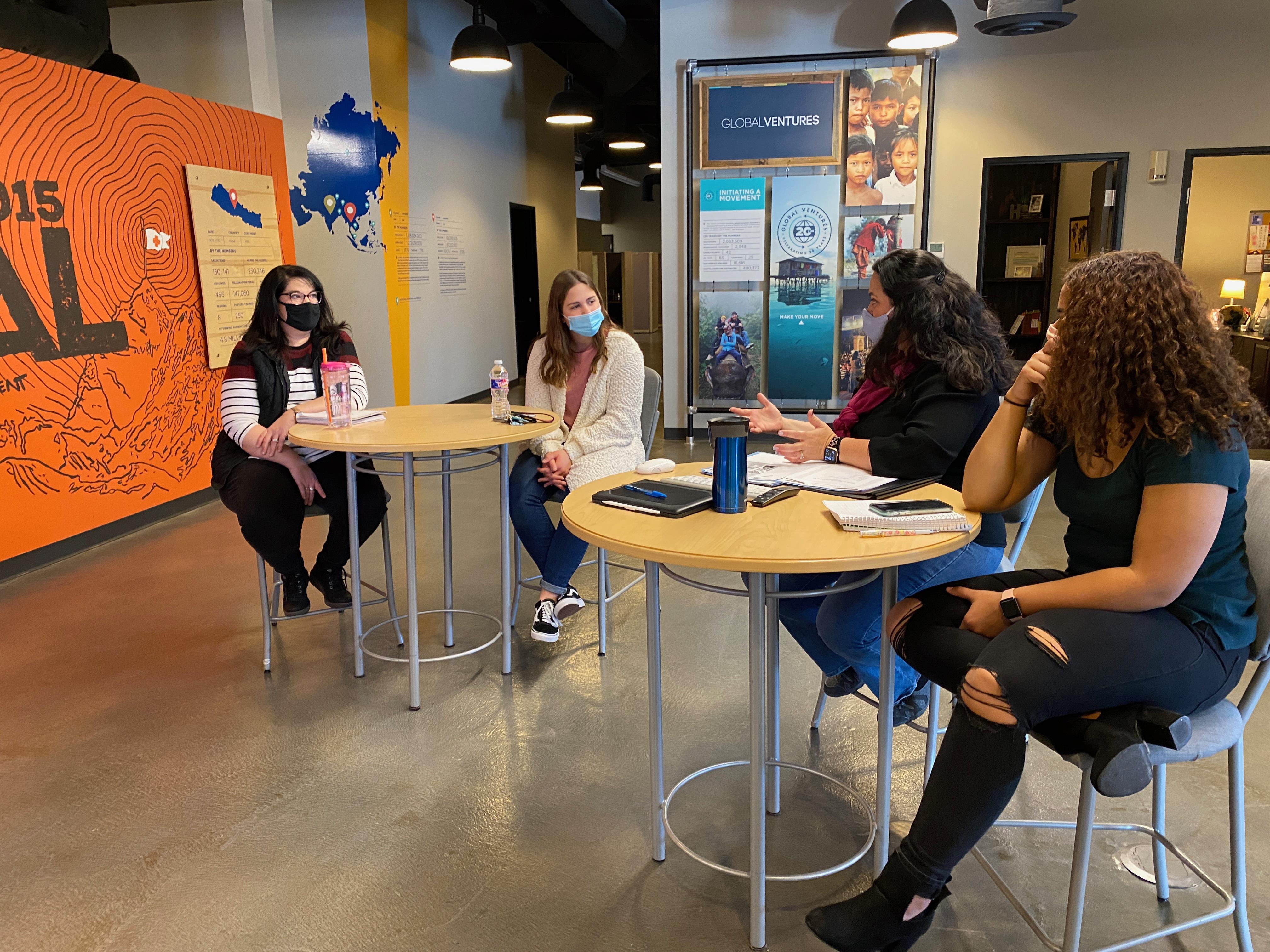 A group of women sitting at tables wearing face masks