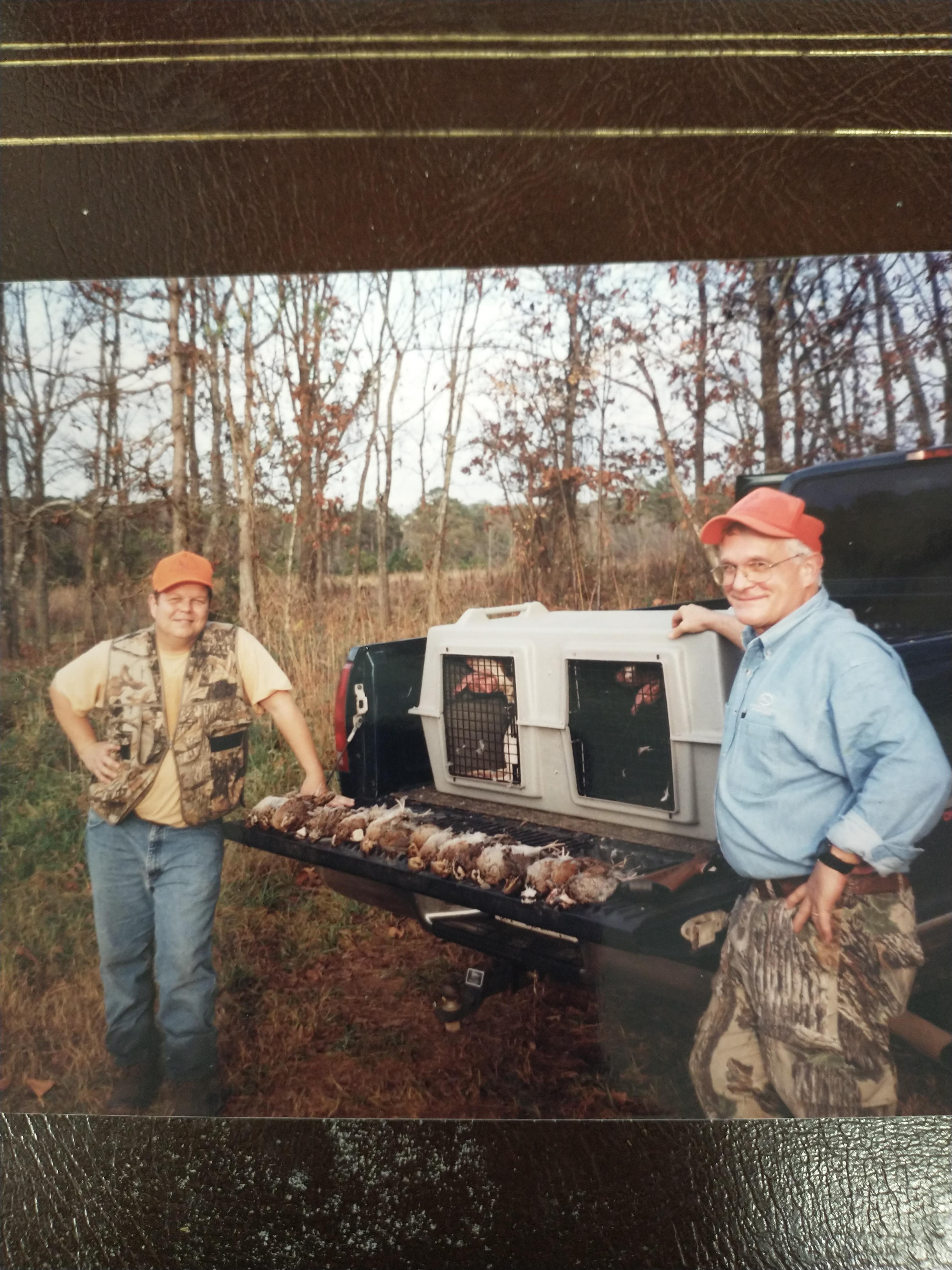 Two men standing next to a truck with meat on it