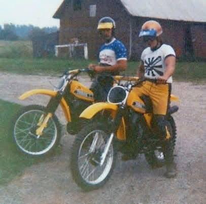 Two men on motorcycles in front of a barn