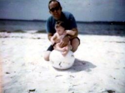 A man holding a baby on a beach