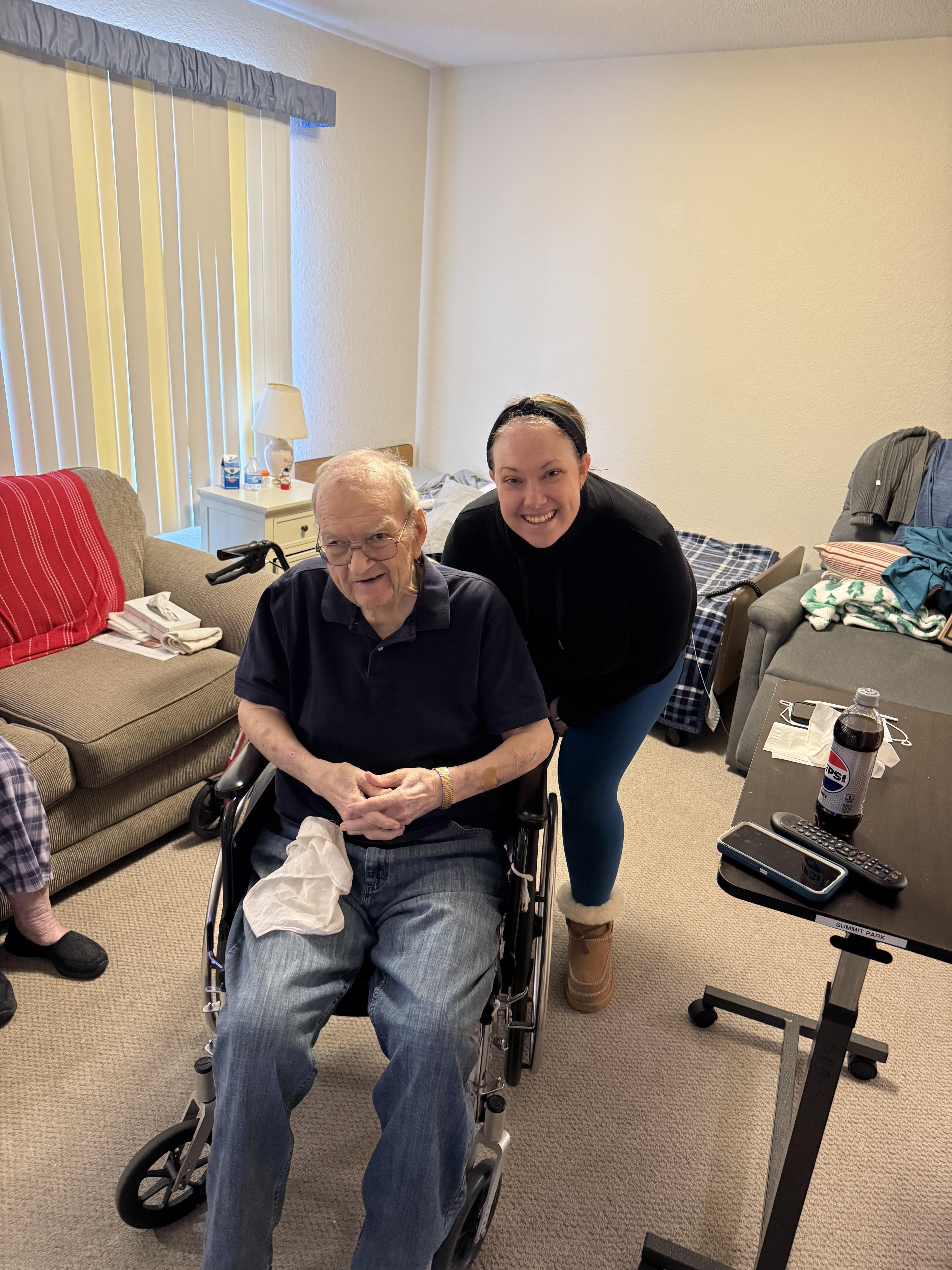 A woman pushing an old man in a wheelchair
