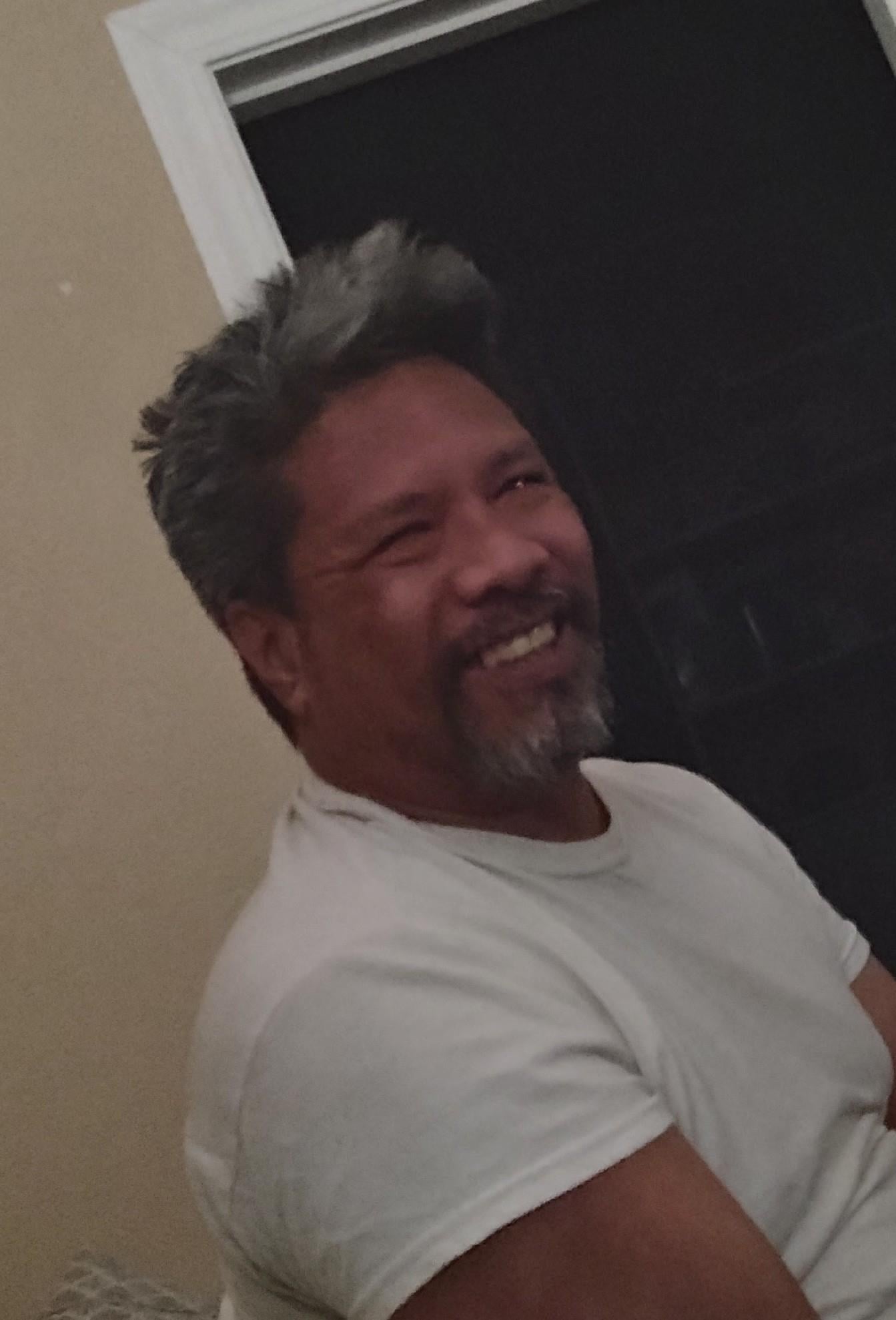 A man with grey hair and beard smiling