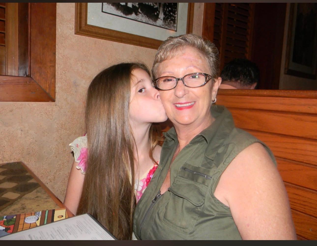 A girl kissing a woman on the cheek