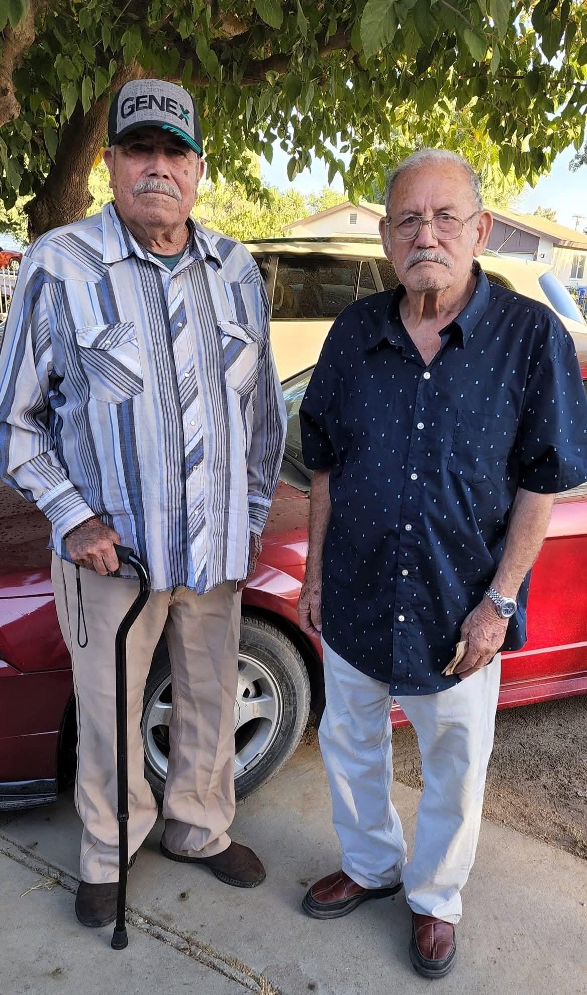Two men standing next to a car