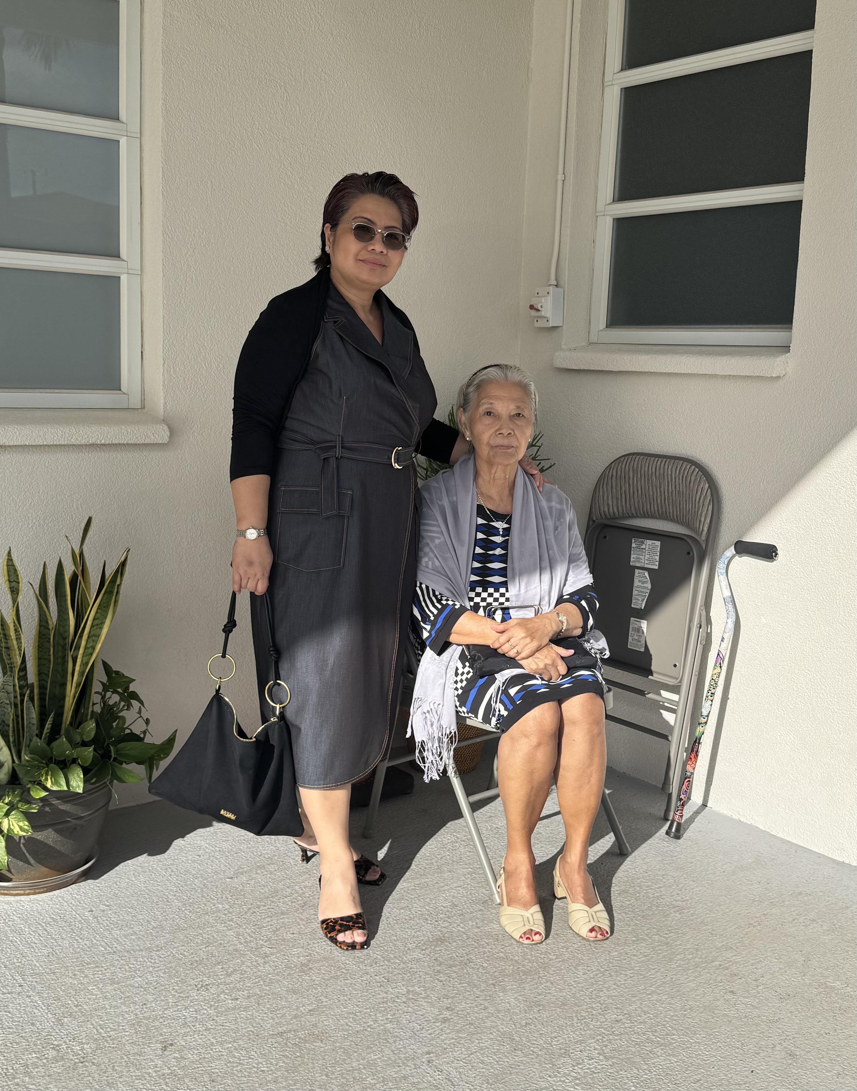 A woman standing next to a woman sitting on a chair