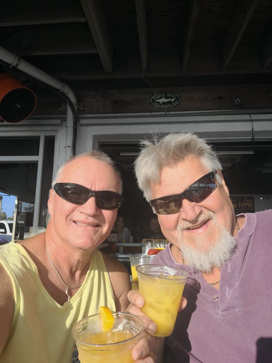 Two men wearing sunglasses and holding drinks