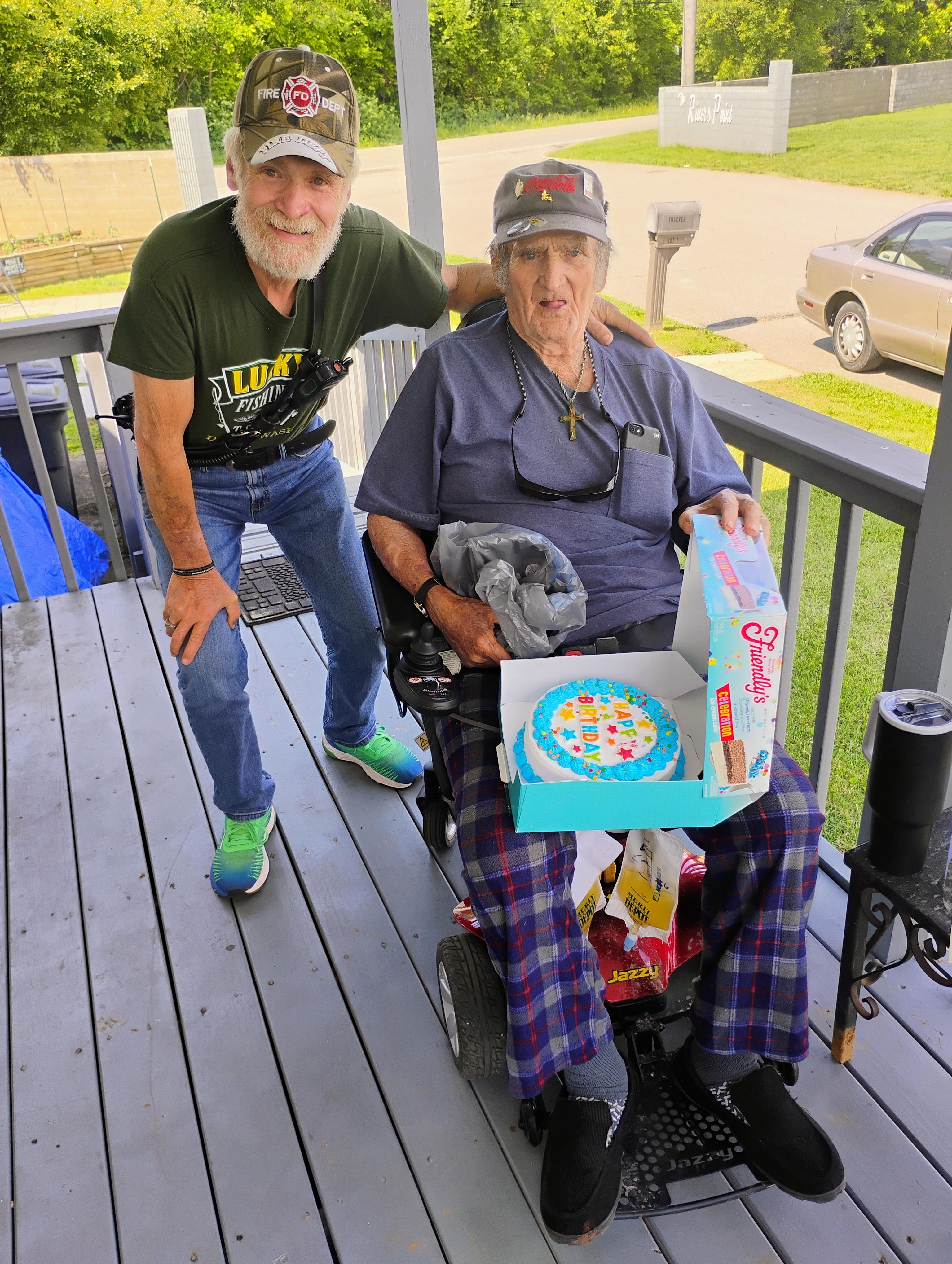 A man standing next to an older woman in a wheelchair