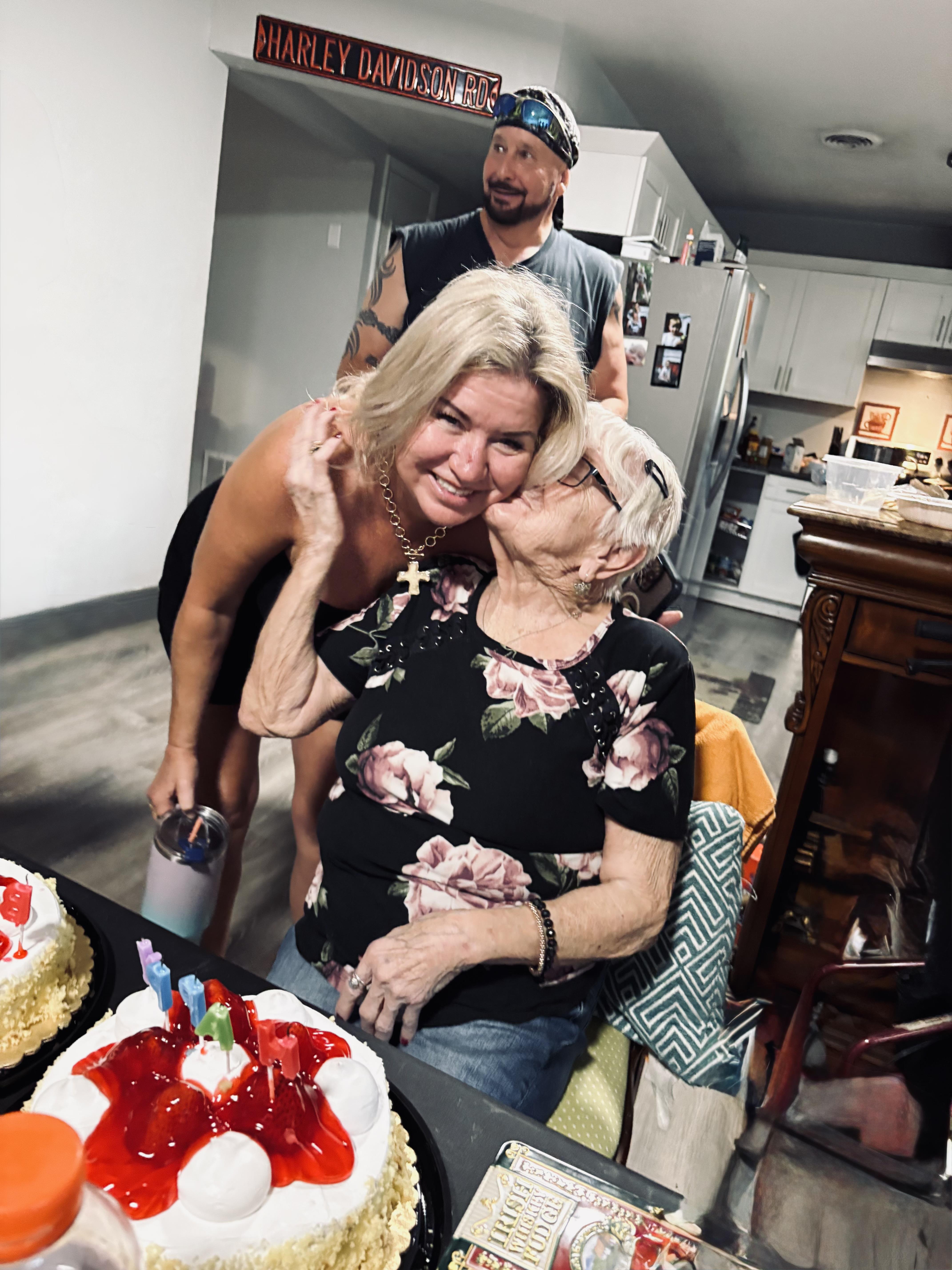 A woman kissing an older woman in a kitchen