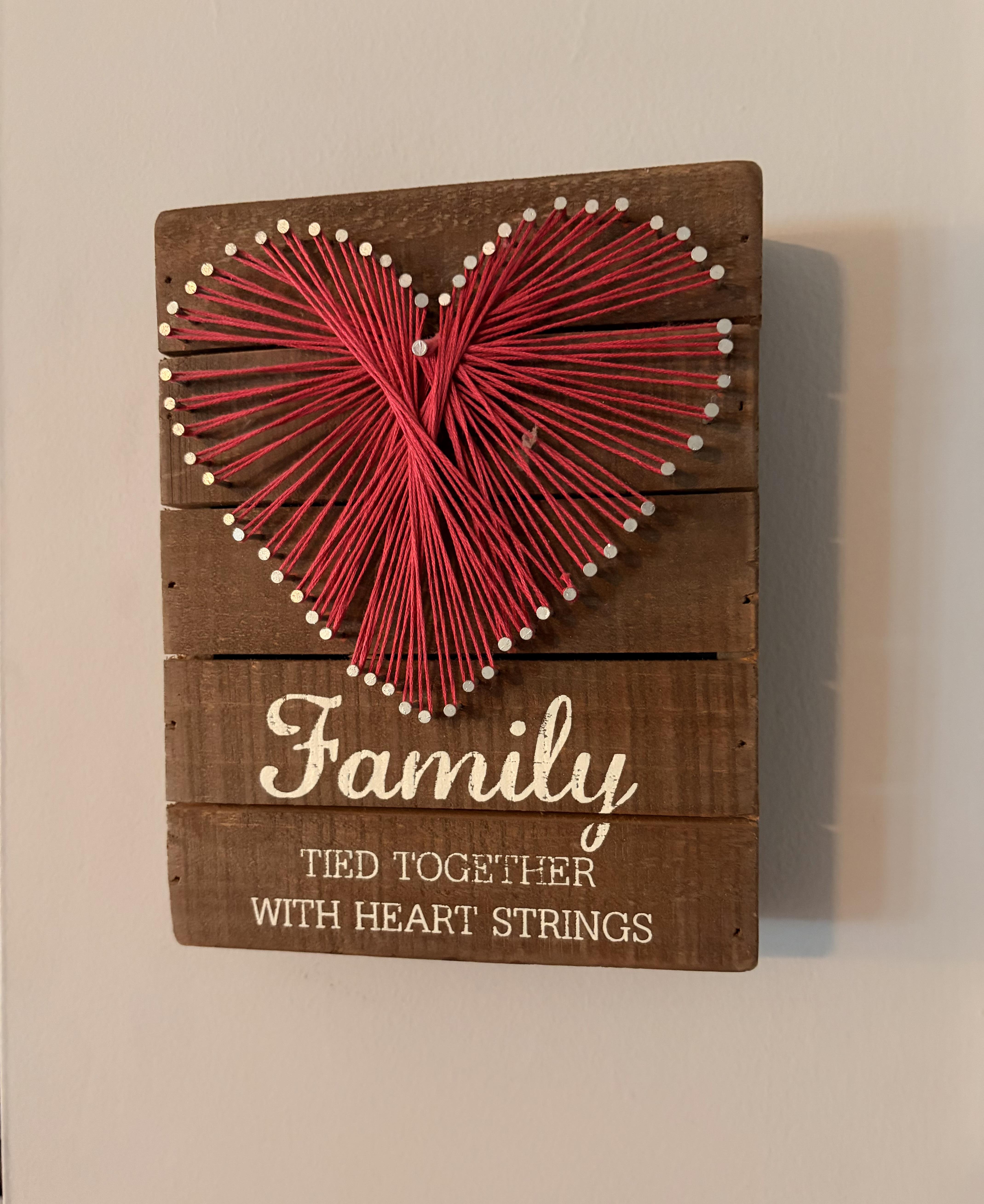 A wooden sign with a heart made of string