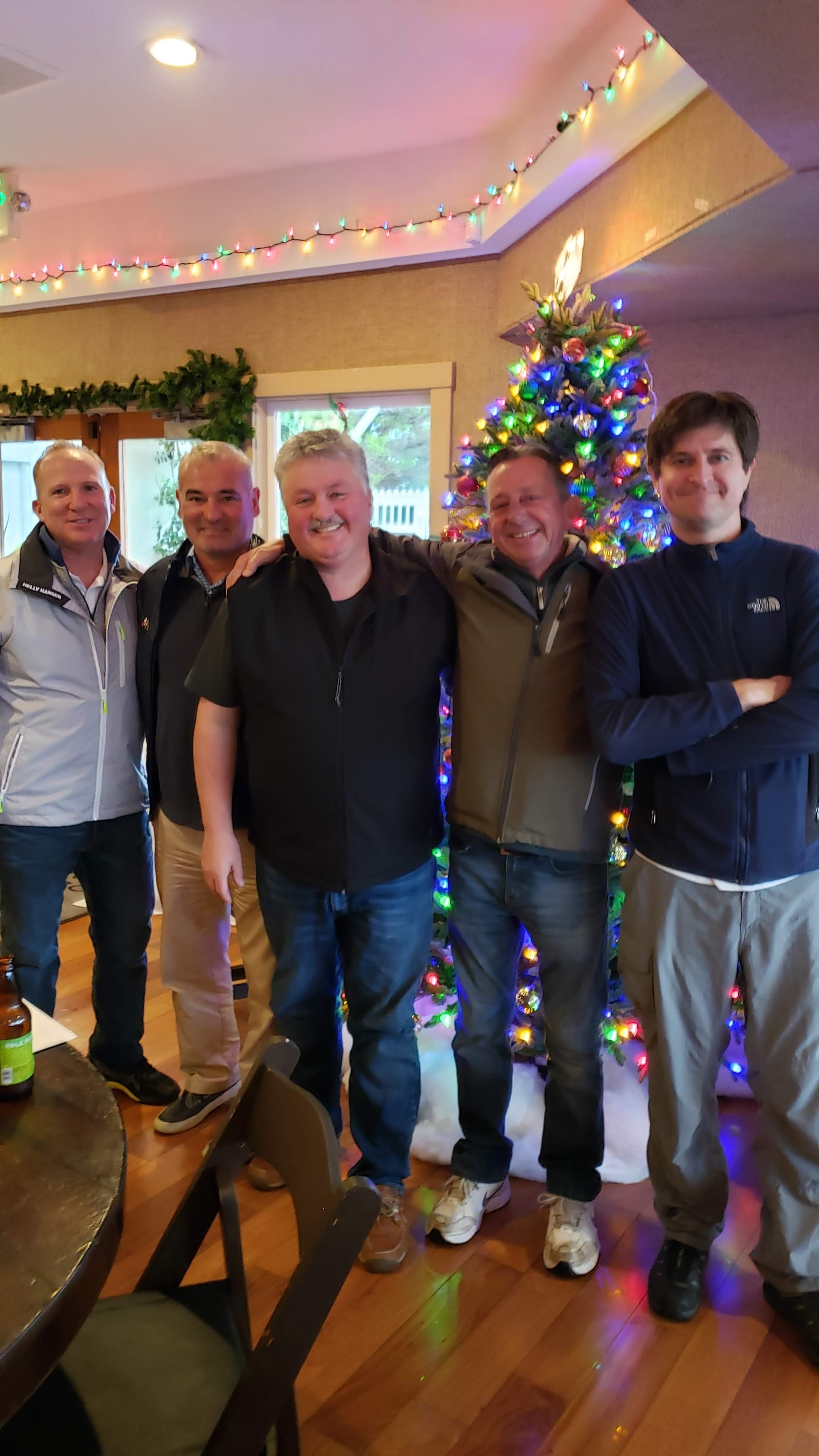 A group of men standing in front of a christmas tree