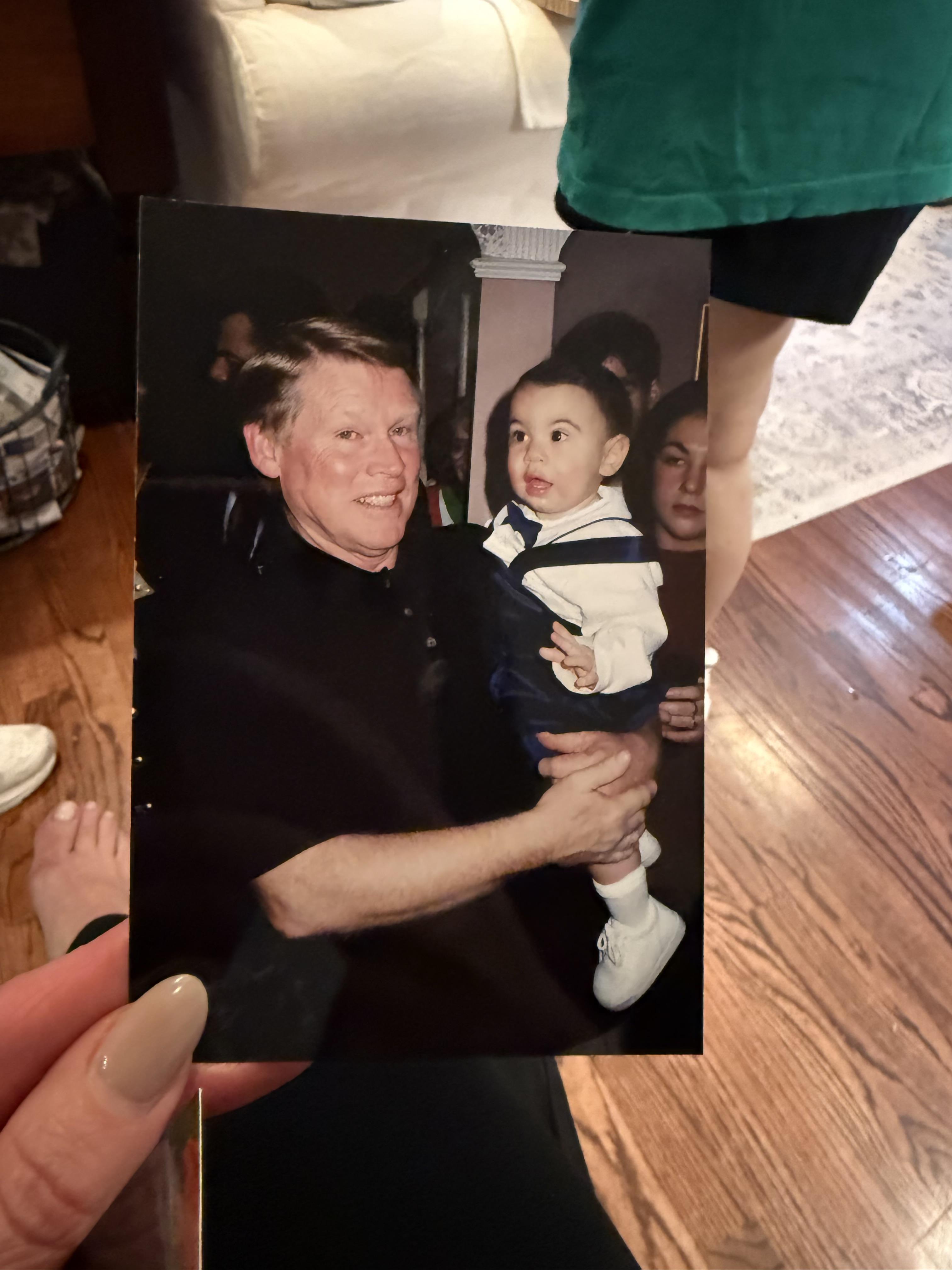 A person holding a photo of a man and a baby