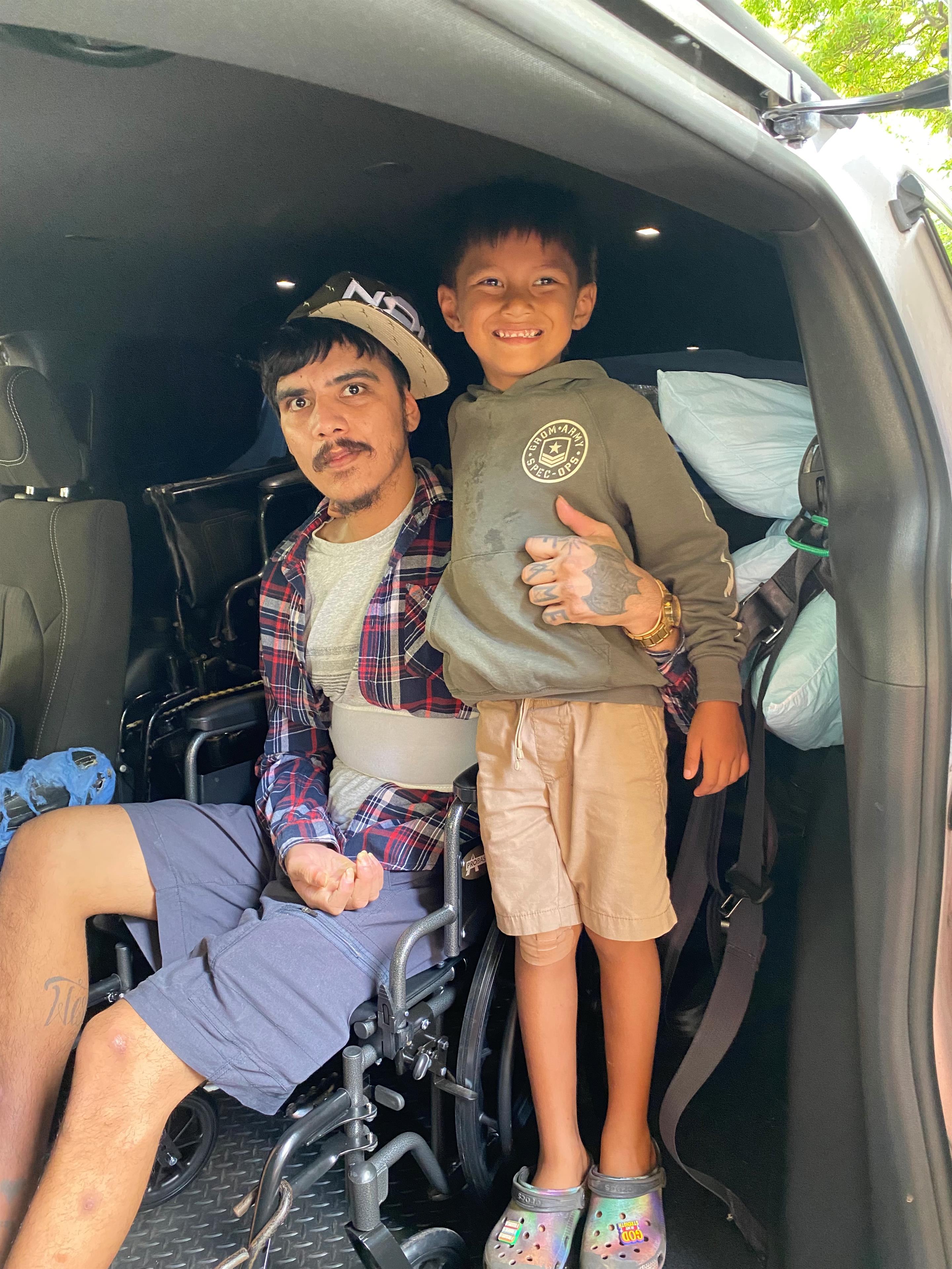 A man and boy in a wheelchair in a car