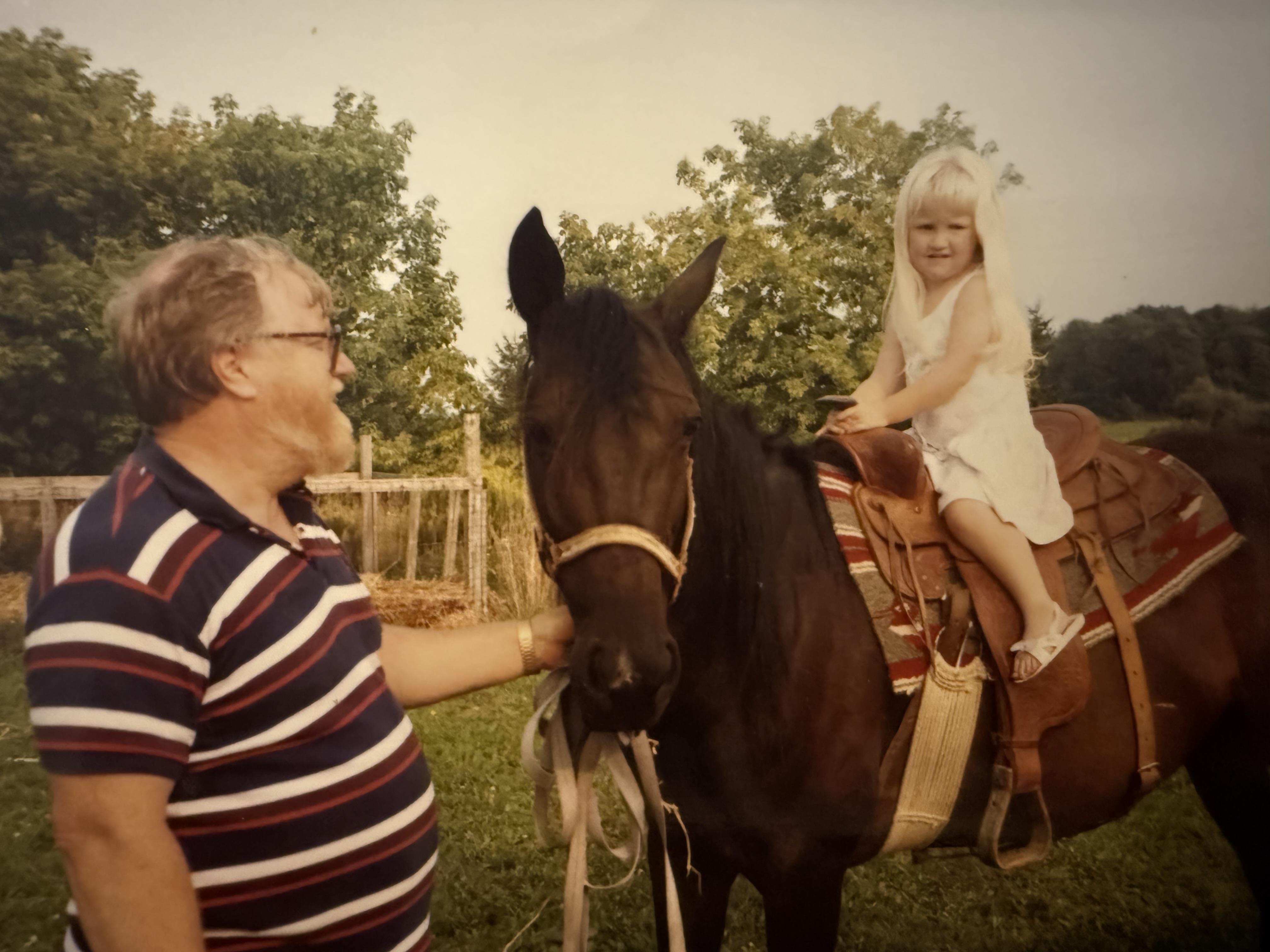 A man petting a girl on a horse