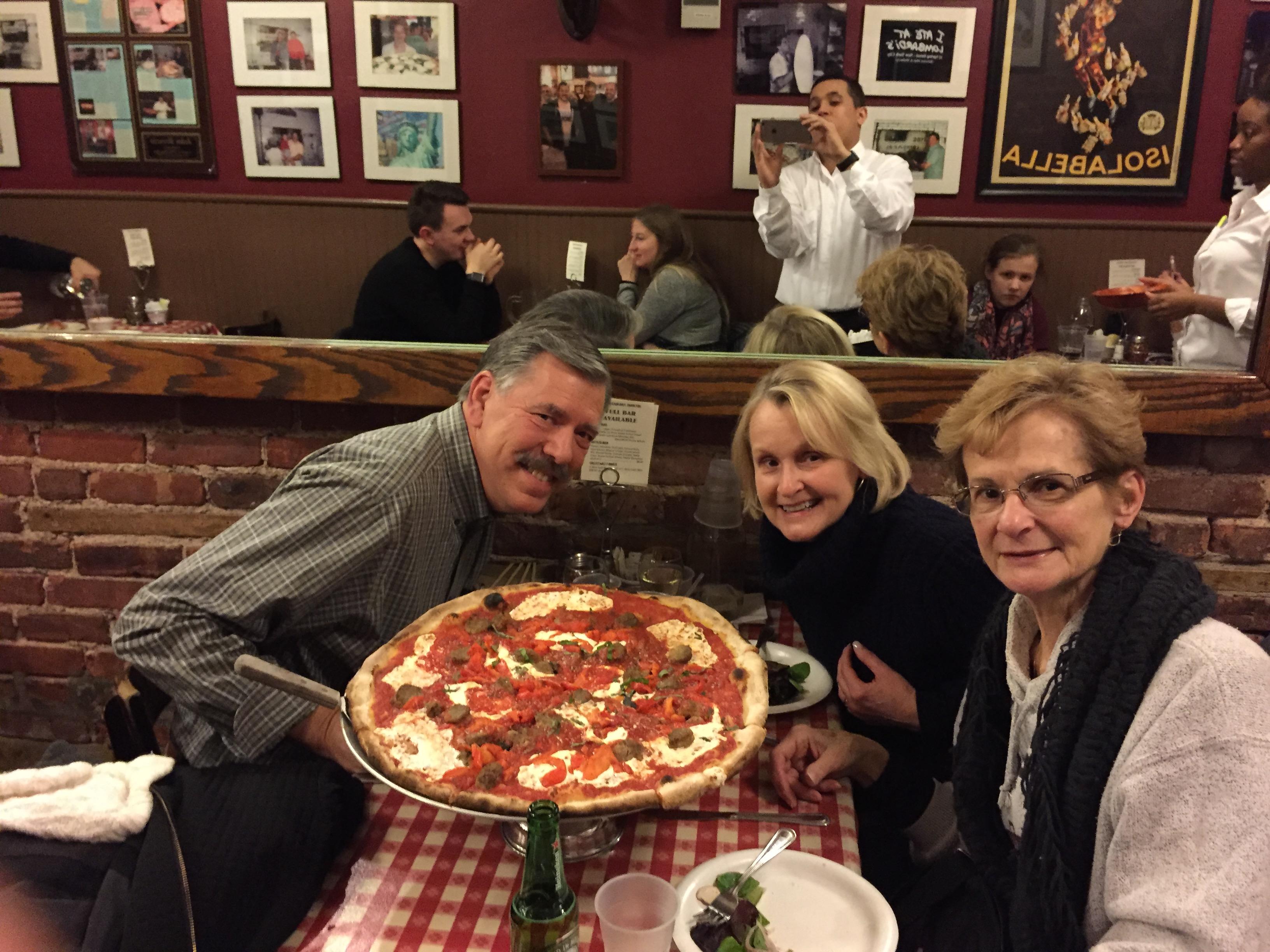 A group of people sitting at a table with a large pizza