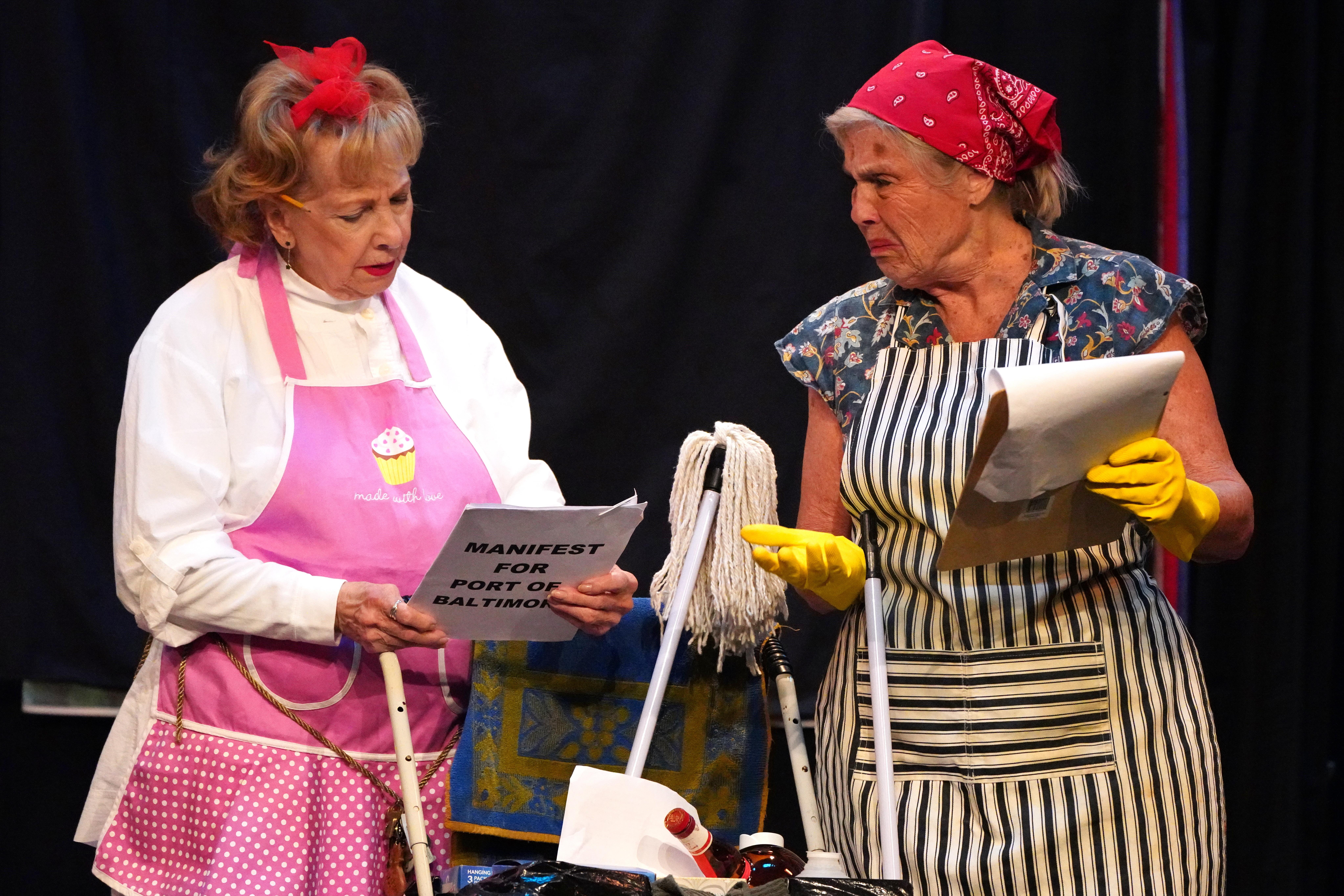 A couple of women wearing aprons and holding papers
