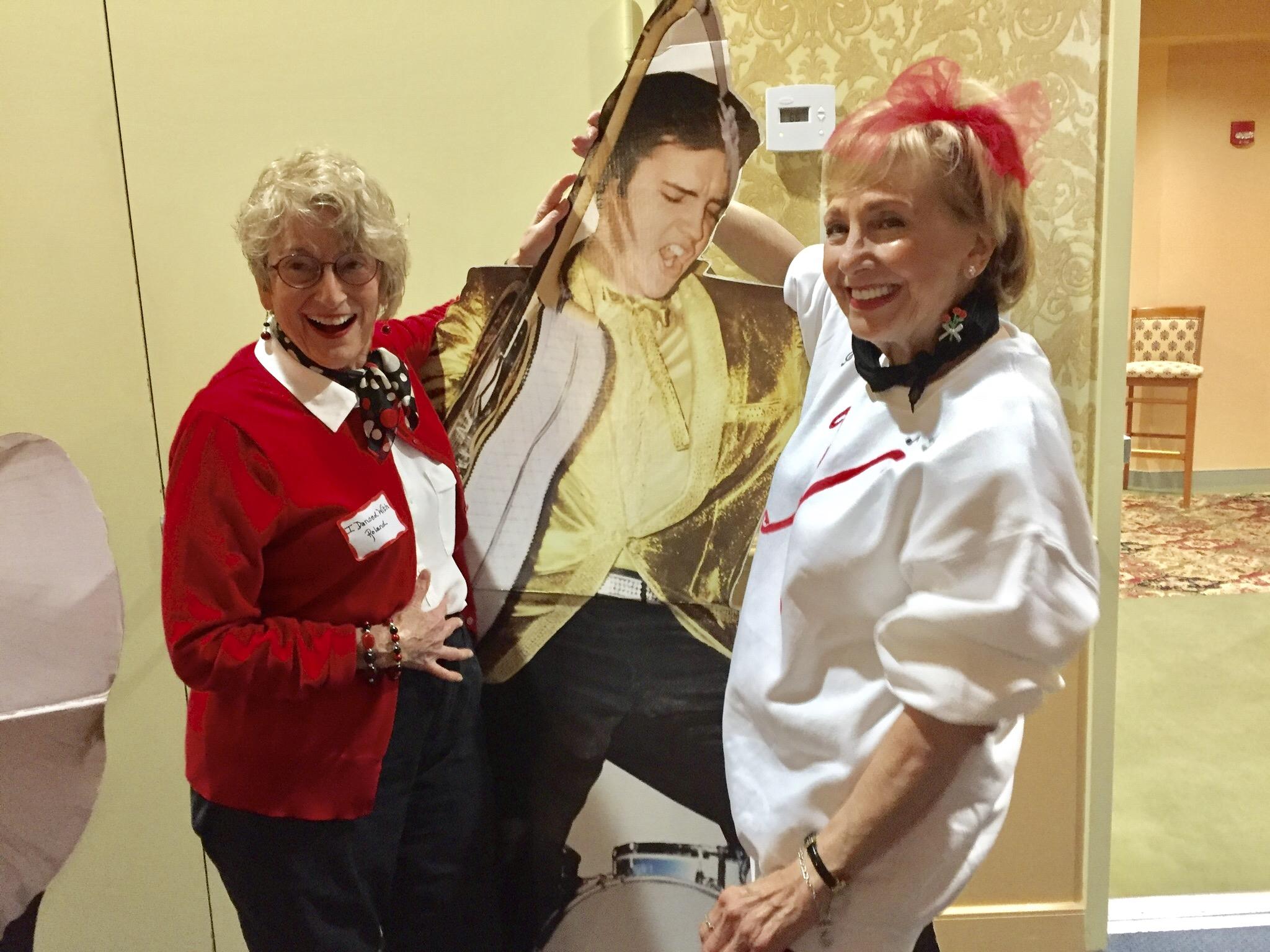 Two women standing next to a cardboard cutout of a man