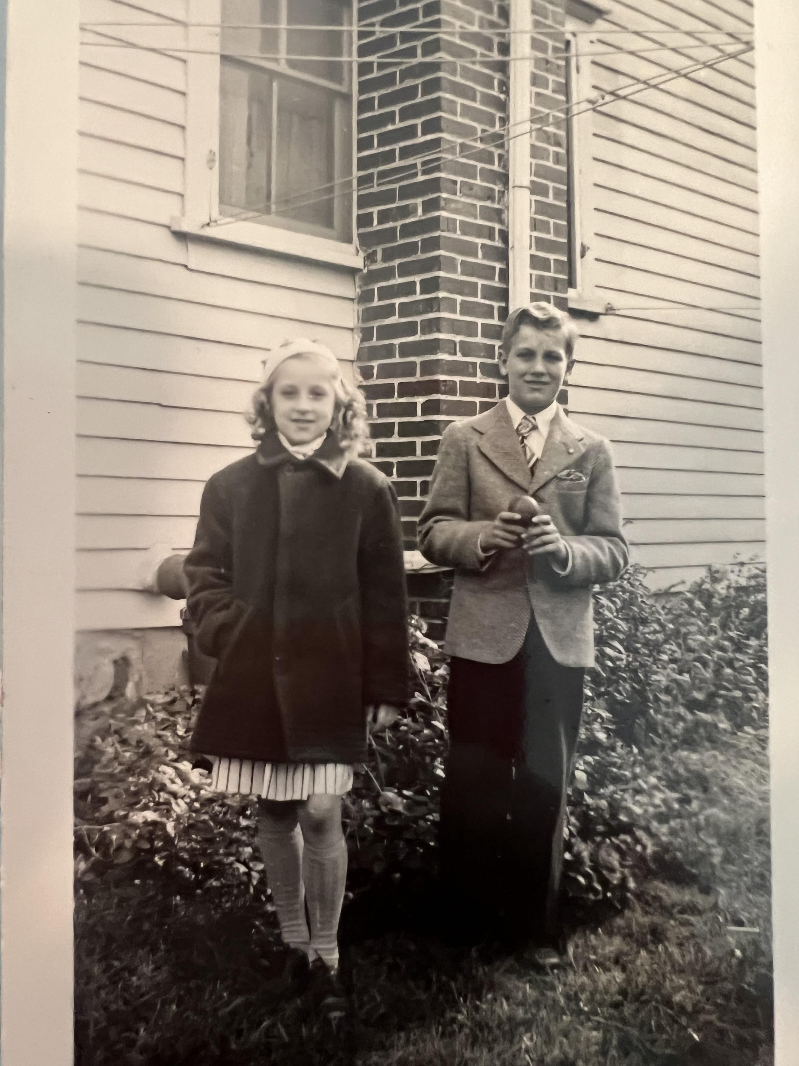A boy and girl standing outside a house