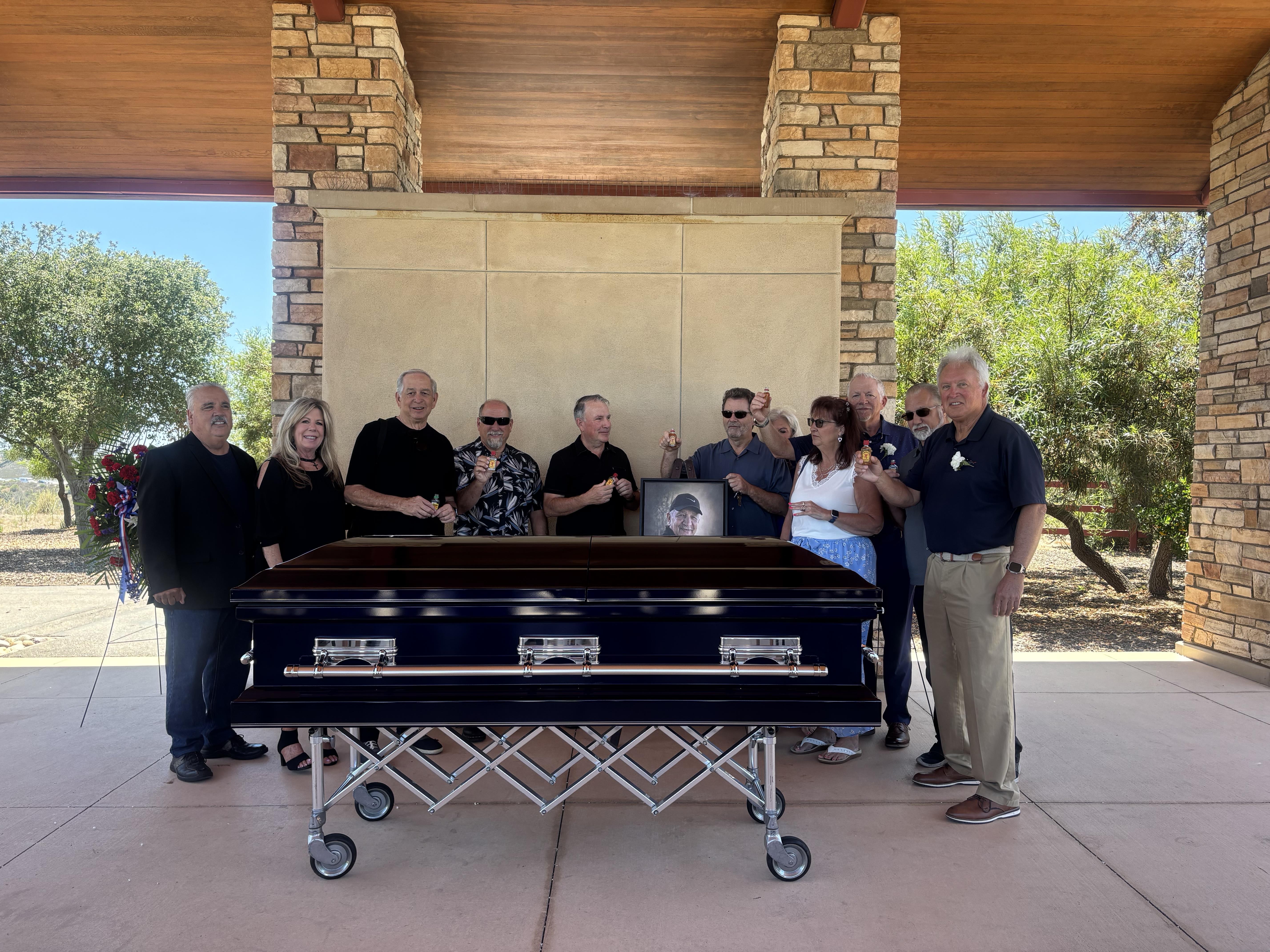 A group of people standing around a coffin