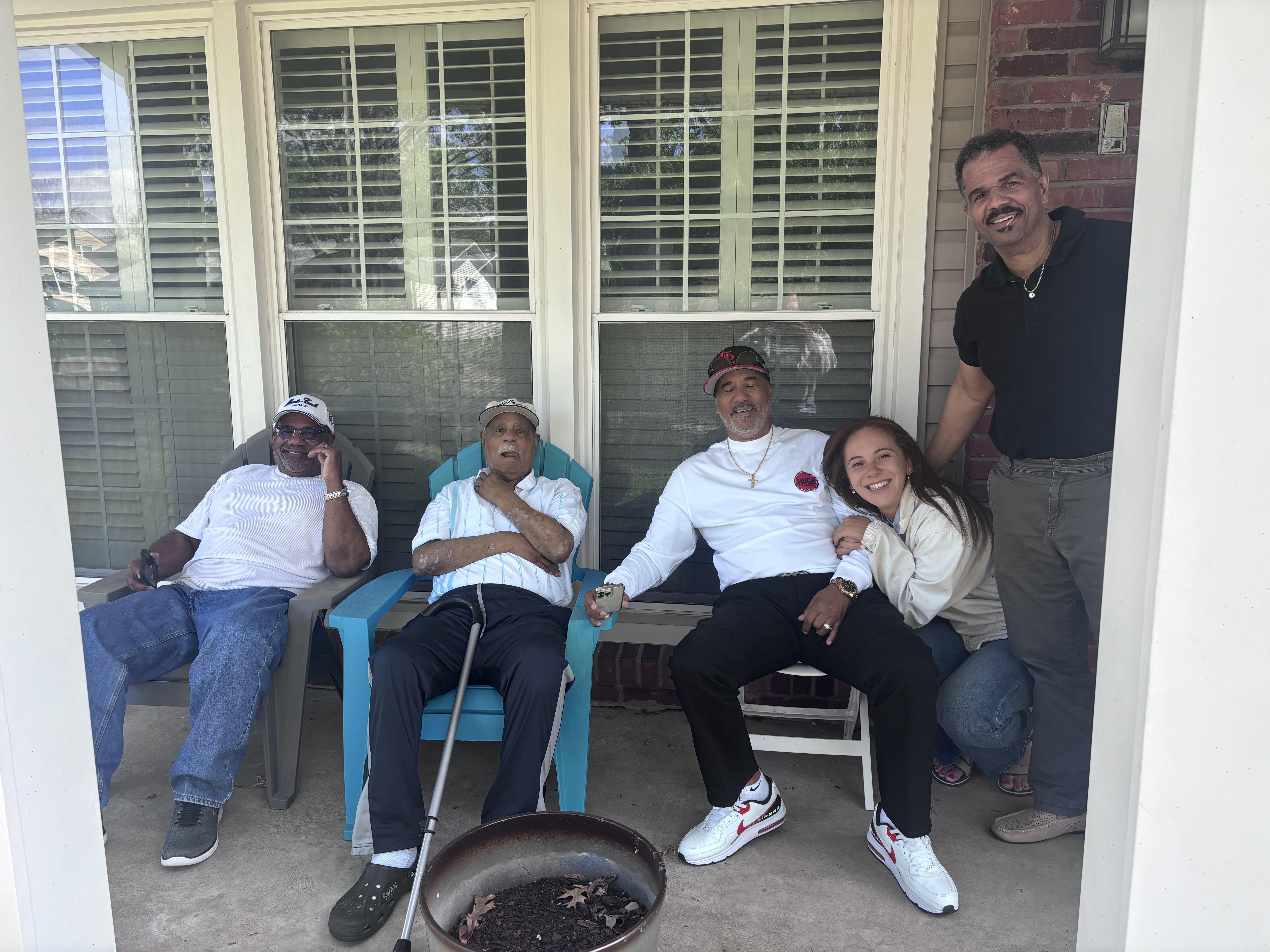A group of people sitting on chairs outside a house