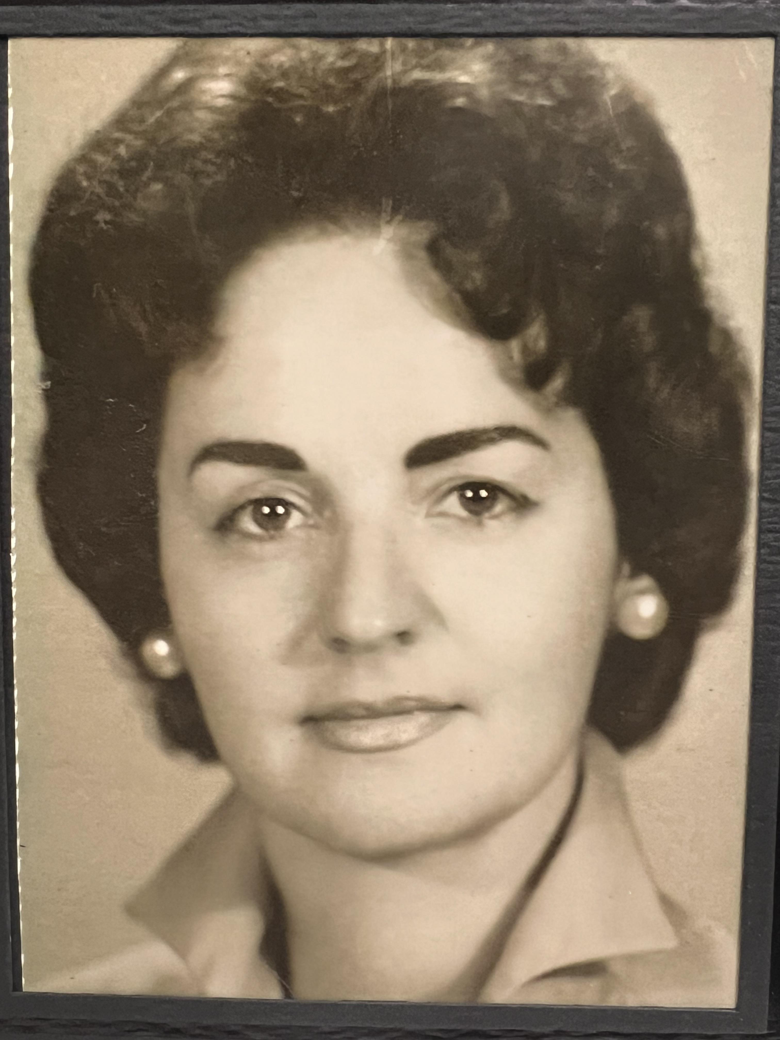 A woman with dark hair and pearl earrings