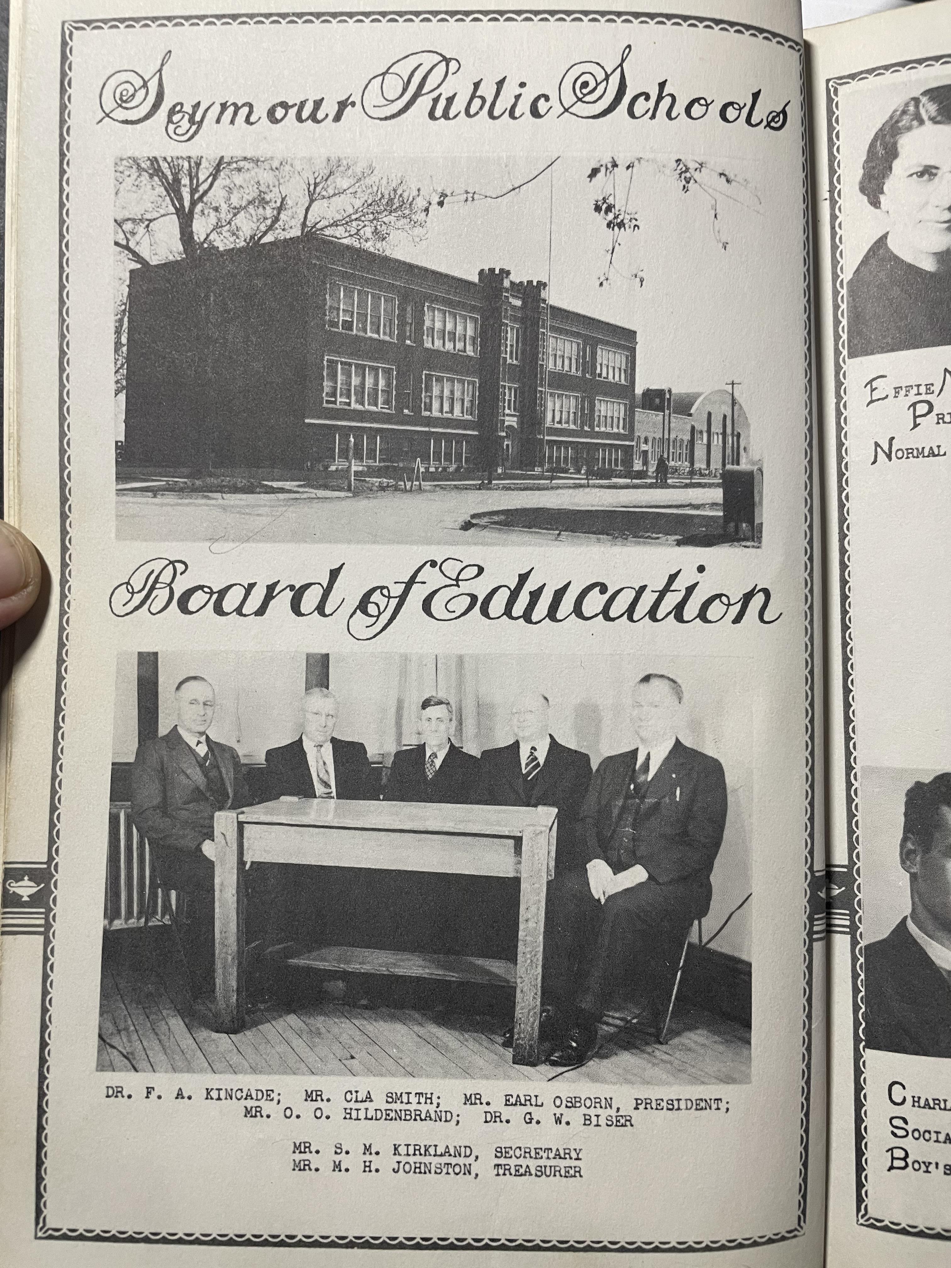 A black and white photo of a group of men sitting at a desk
