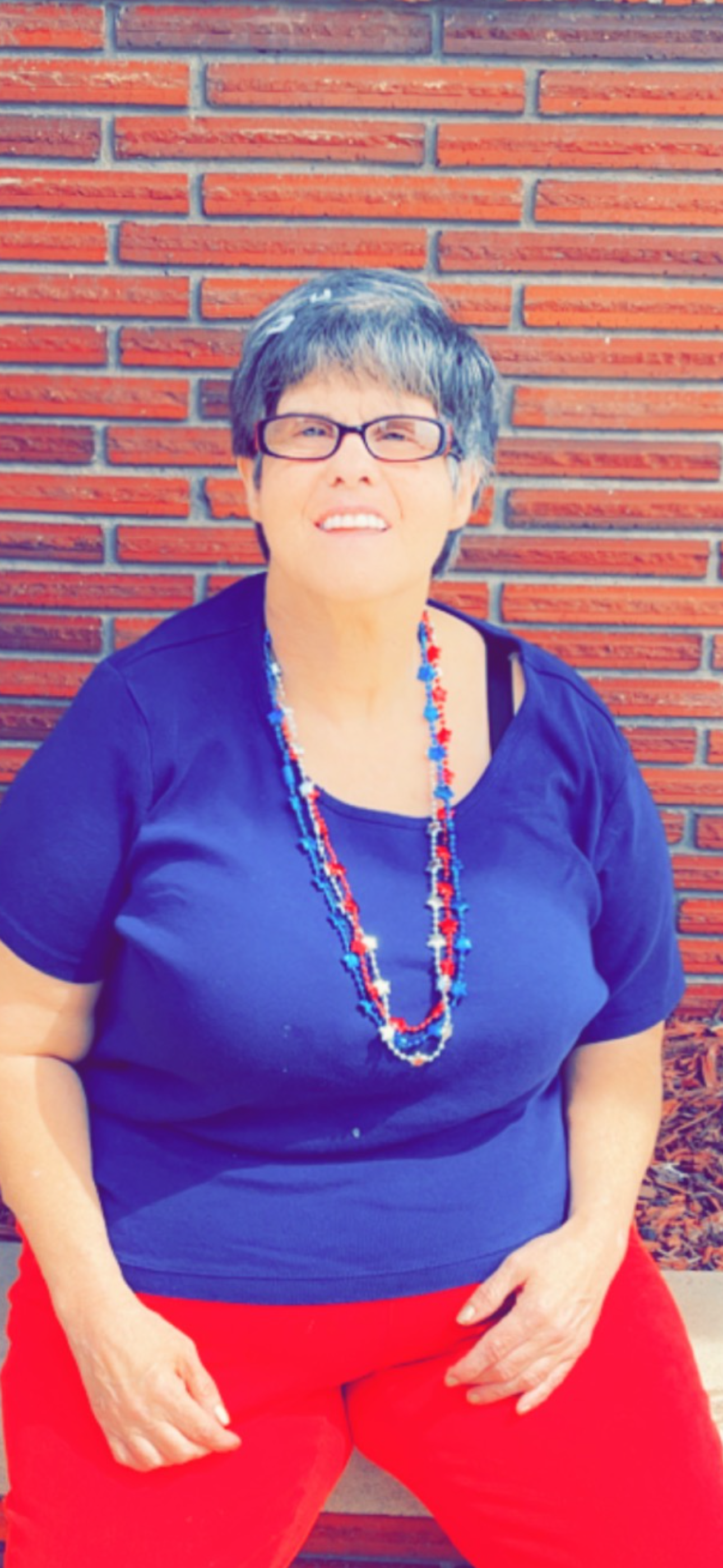 A woman wearing a blue shirt and a red and white necklace