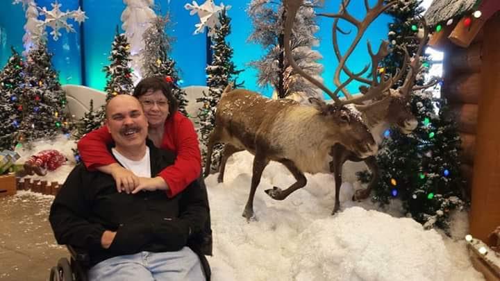 A man and woman posing for a picture with a reindeer