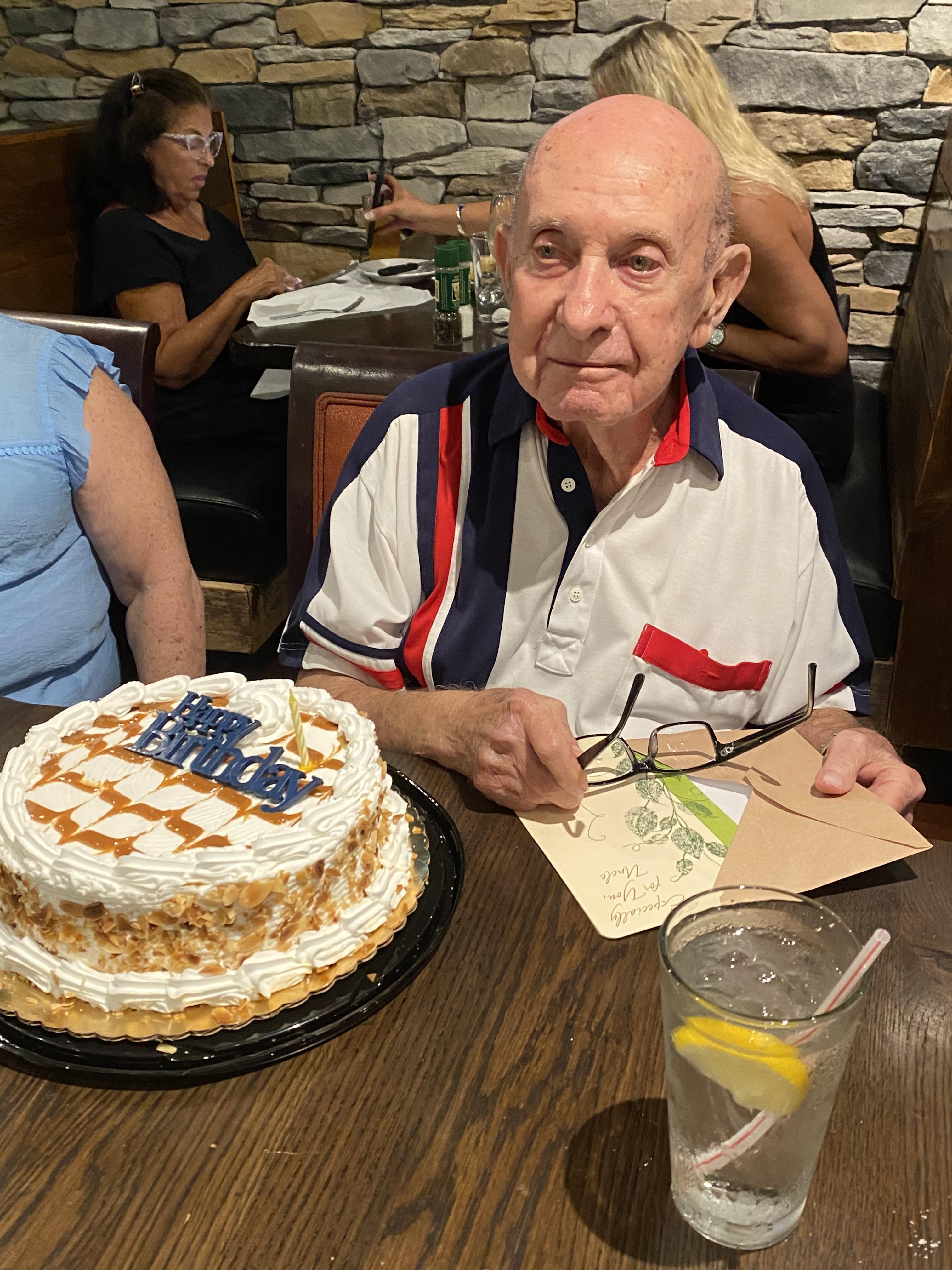 An old man sitting at a table with a birthday cake