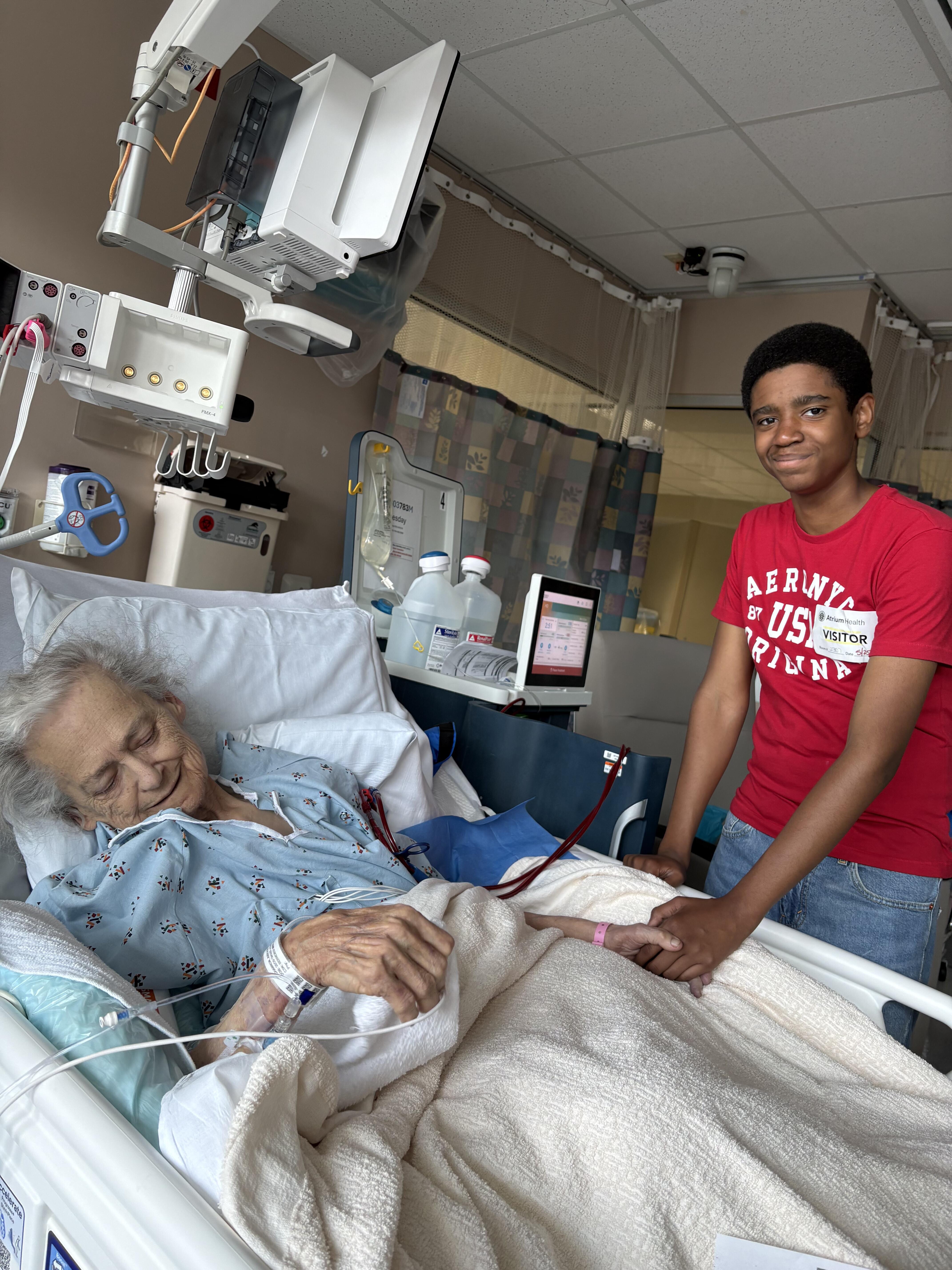 A boy standing next to a woman in a hospital bed