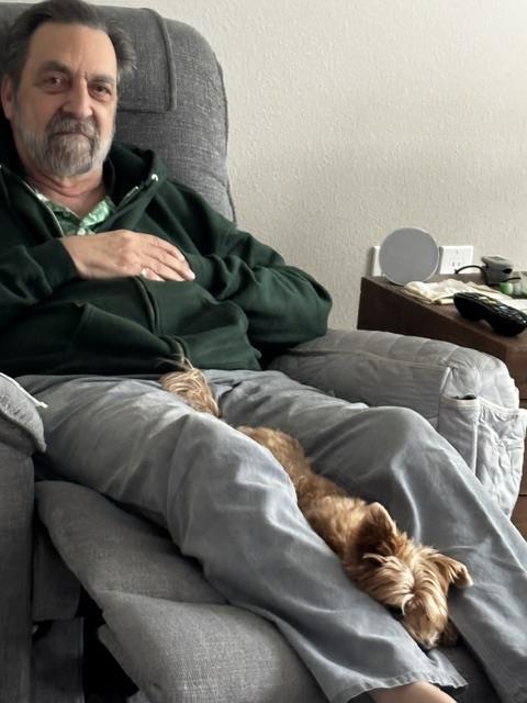A man sitting in a chair with a dog on his lap