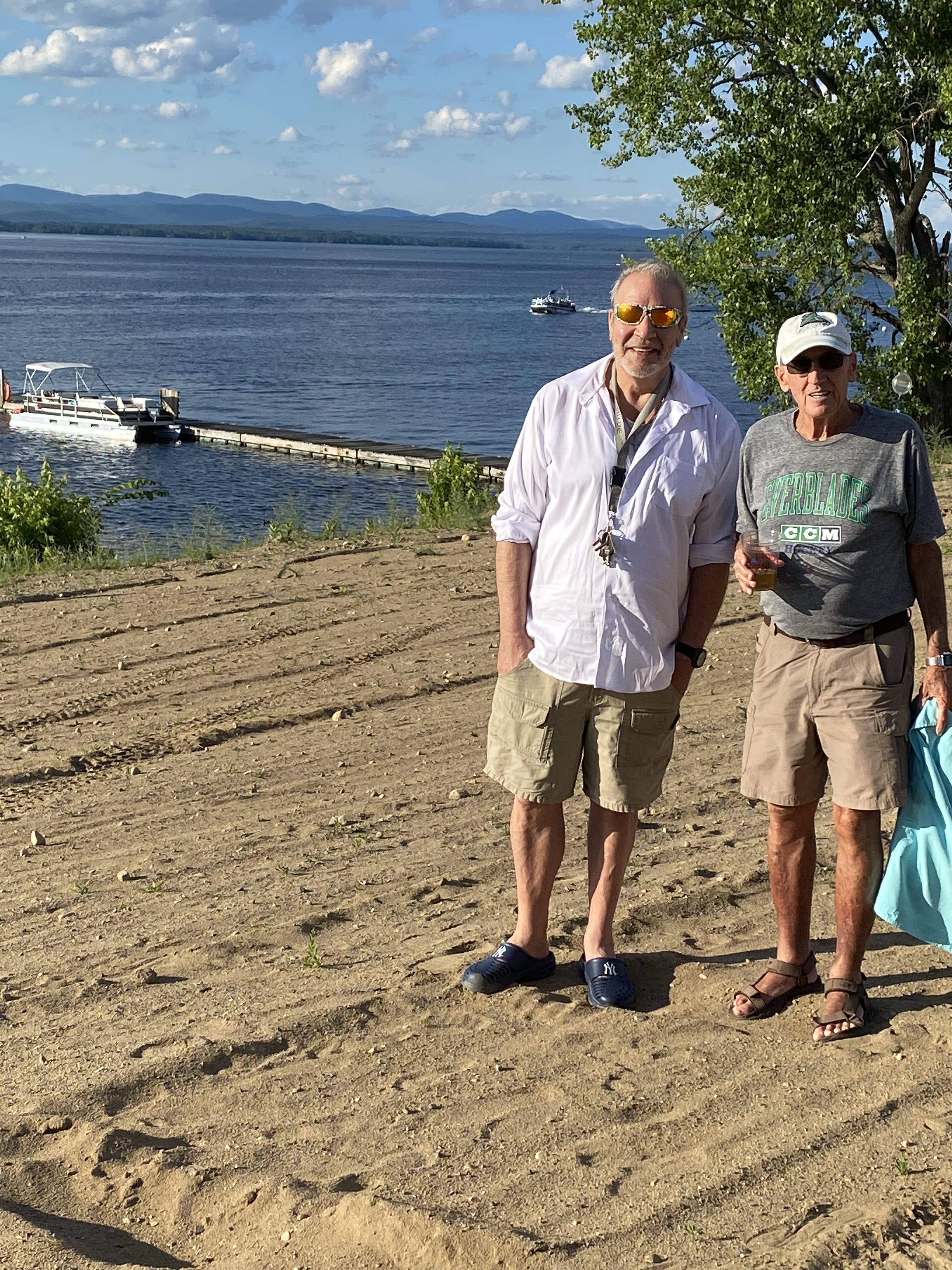 Two men standing on a dirt path near water