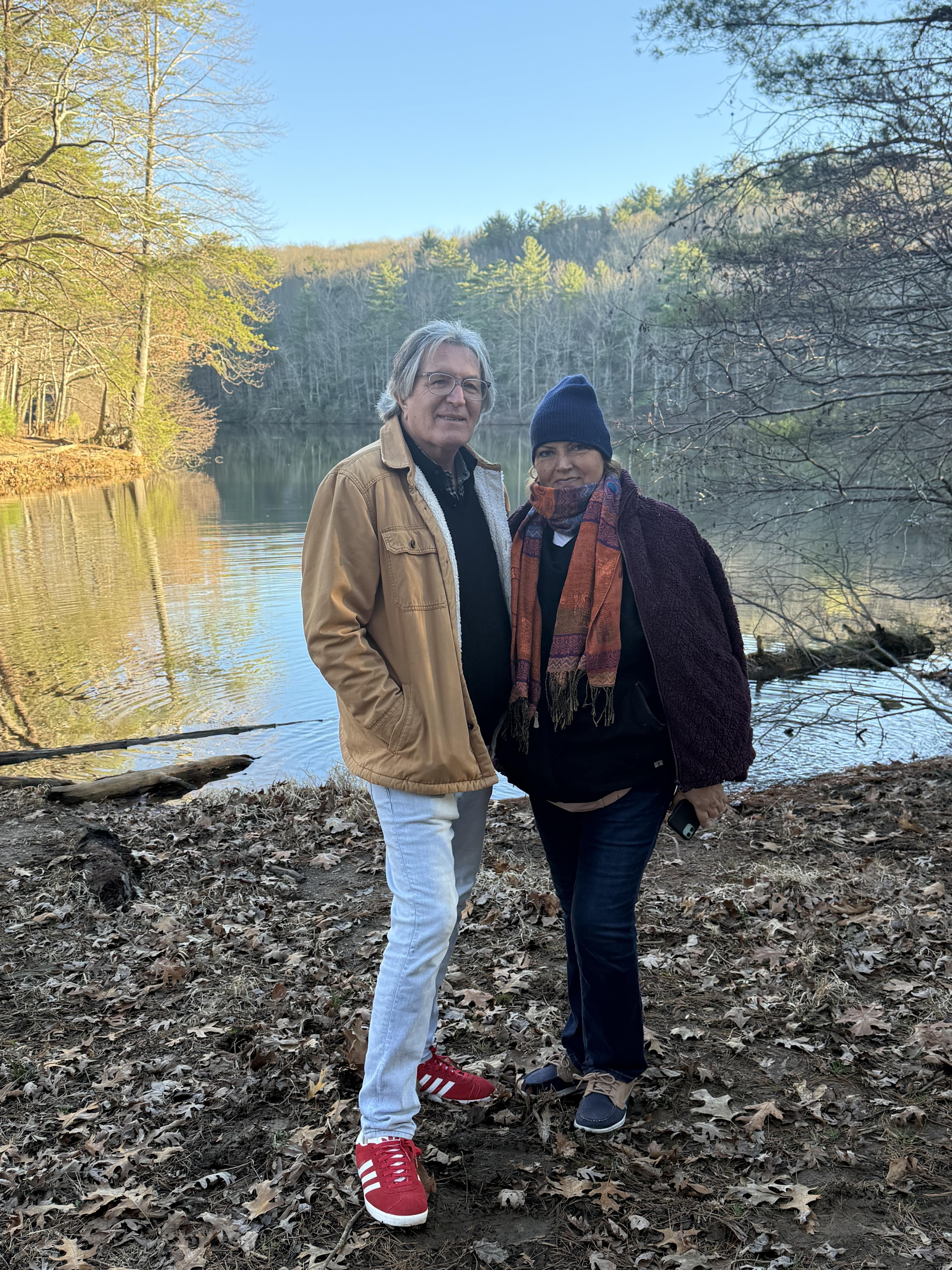 A man and woman standing next to a lake